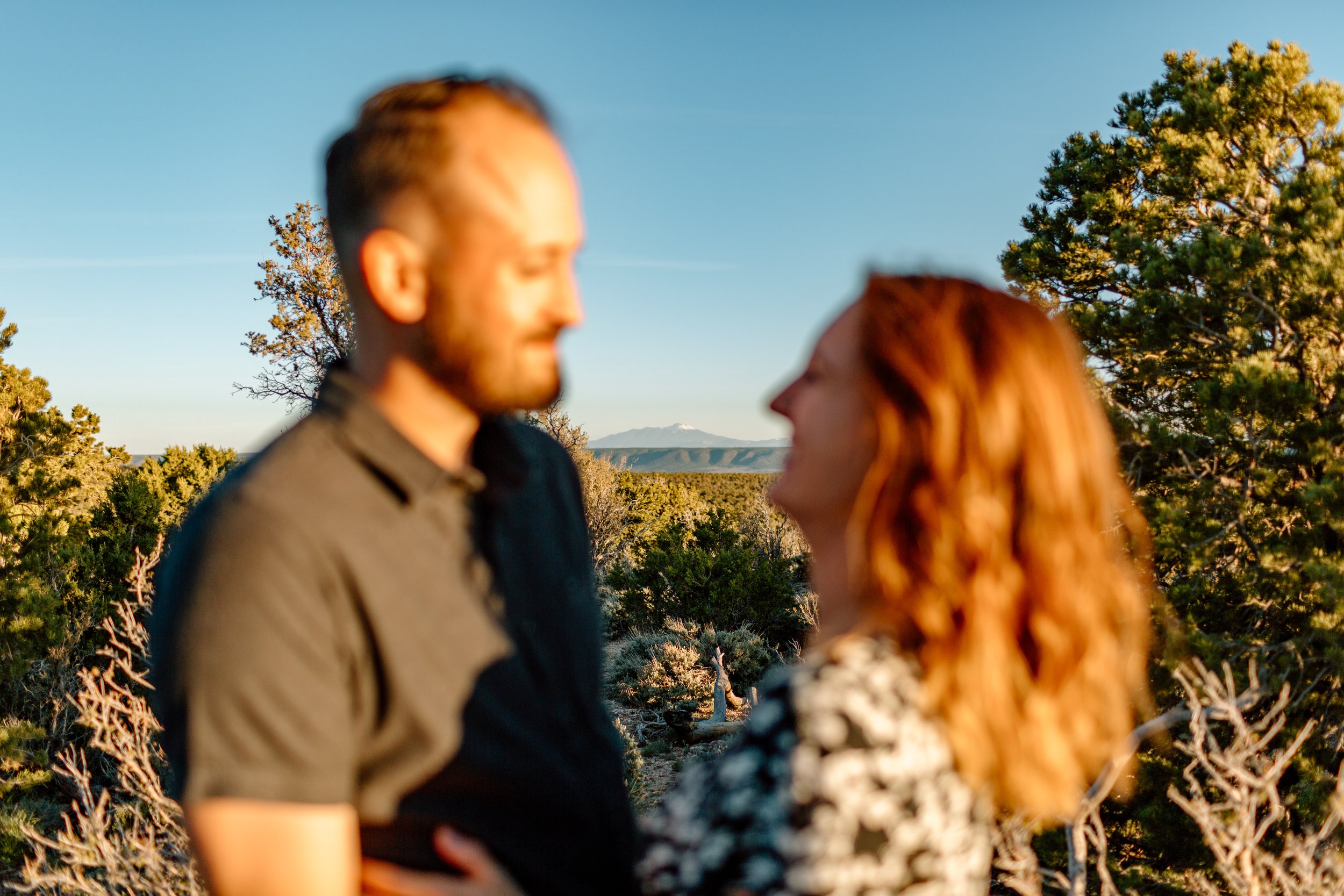  blurry couple smiles at each other with mount humphreys in focus in the distance 