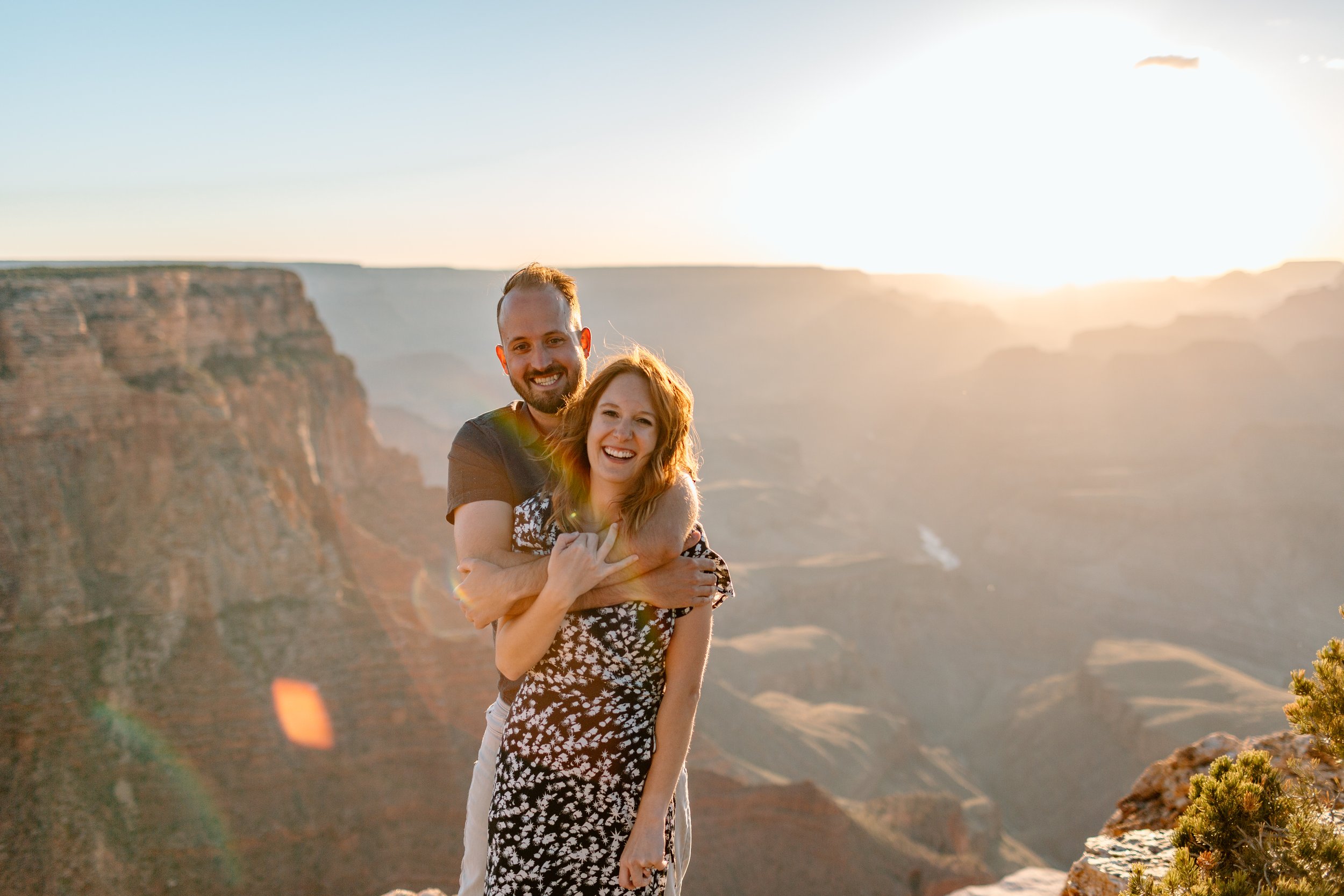  couple snuggles and smiles at camera during their grand canyon sunset engagement session 