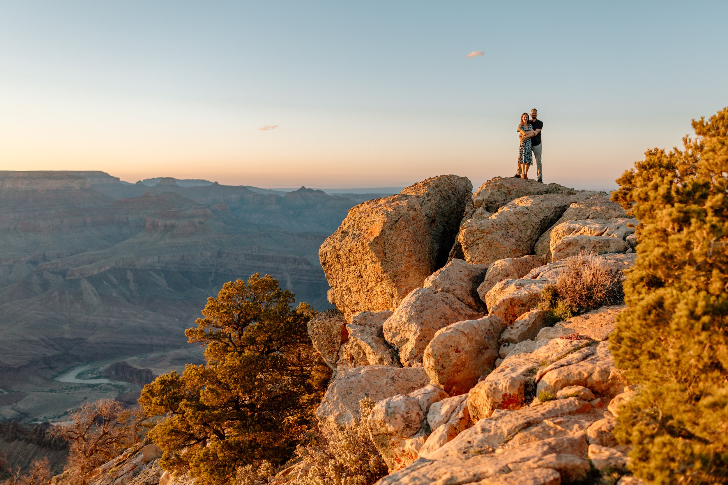  distant couple holds each other during golden hour at the grand canyon 