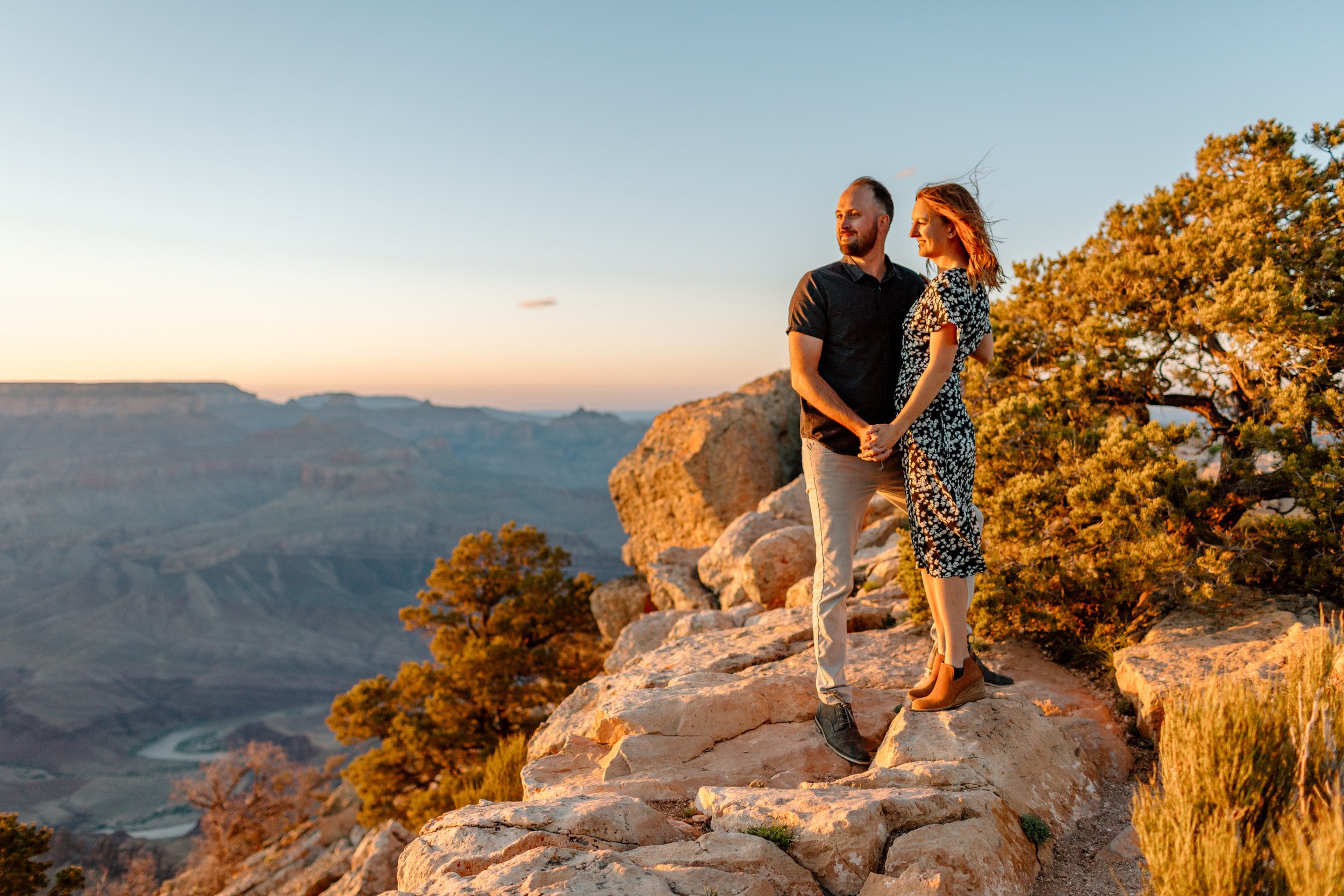  couple illuminated by golden glow as they look out into the grand canyon sunset at lipan point 