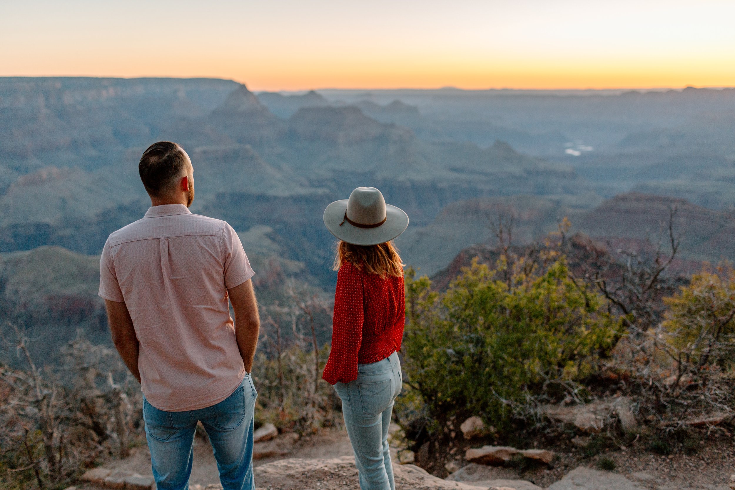  couple looks out towards sunrise at grandview point at the grand canyon 