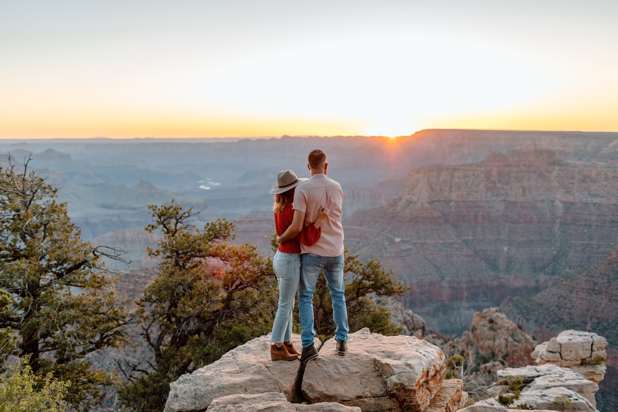  couple holds each other and watches the sunrise during their grand canyon engagement session 