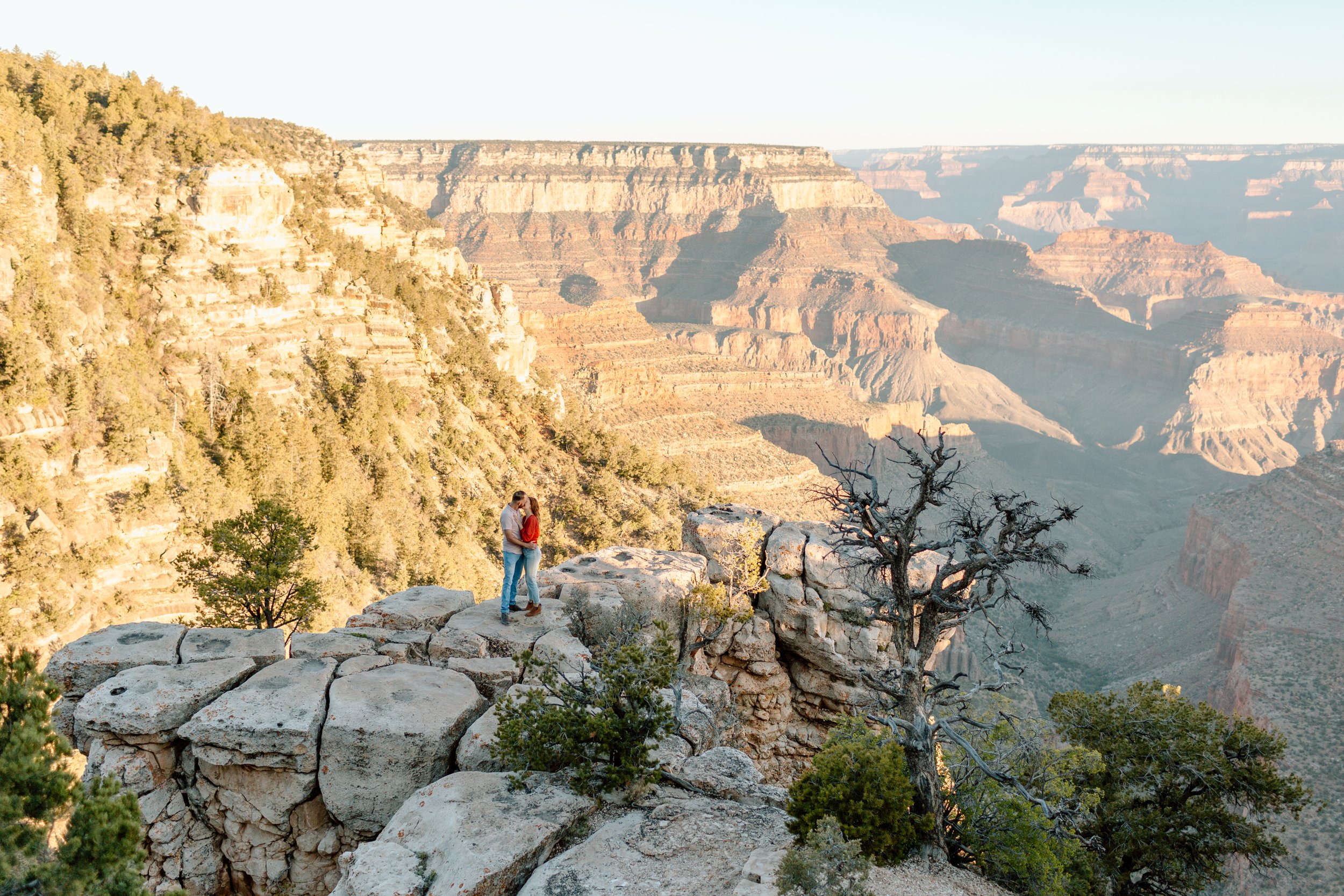  distant couple kisses on an outcropping for their grand canyon engagement session 