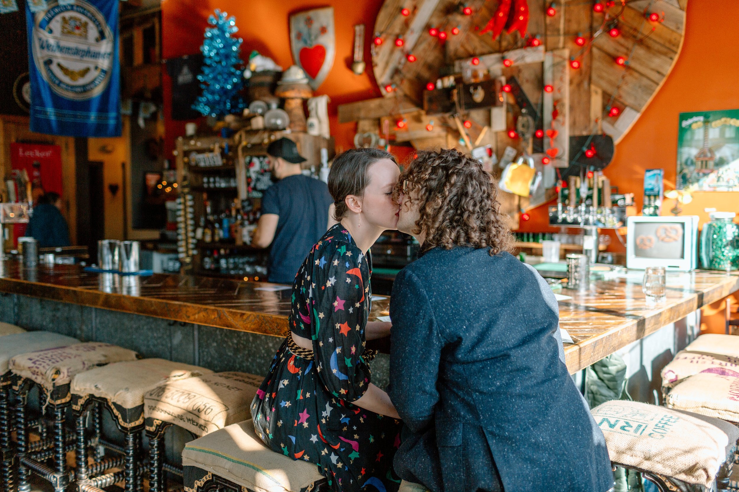  couple kisses while sitting at a bar during their urban elopement 