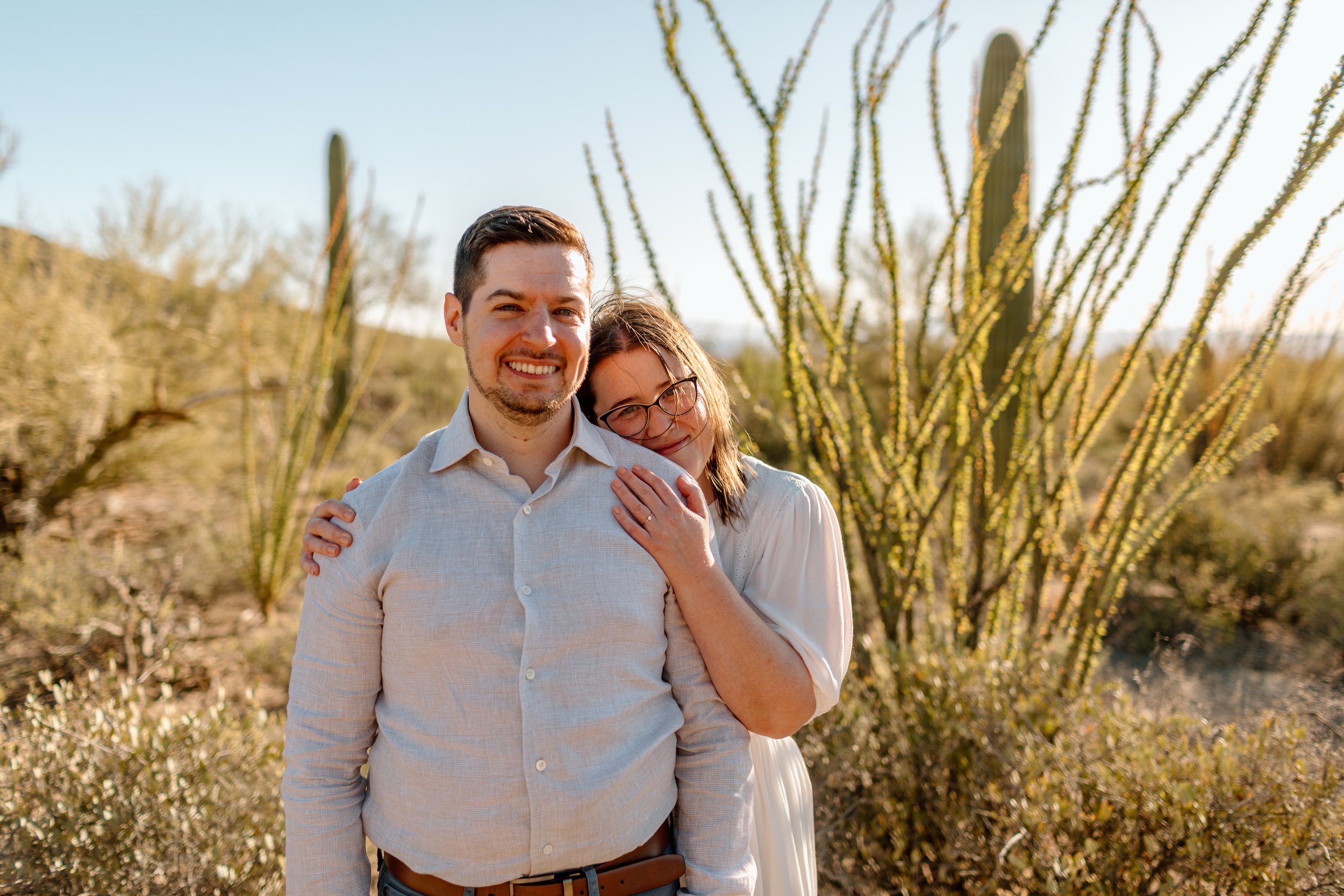  couple cuddles and smiles at the camera during their arizona engagement session 