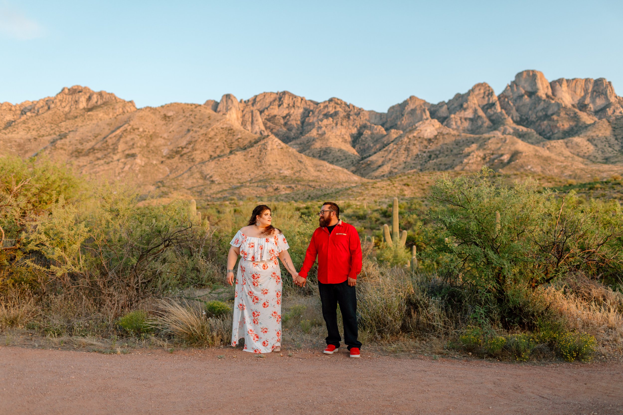  couple holds hands and looks at each other with santa catalina mountains in the background 