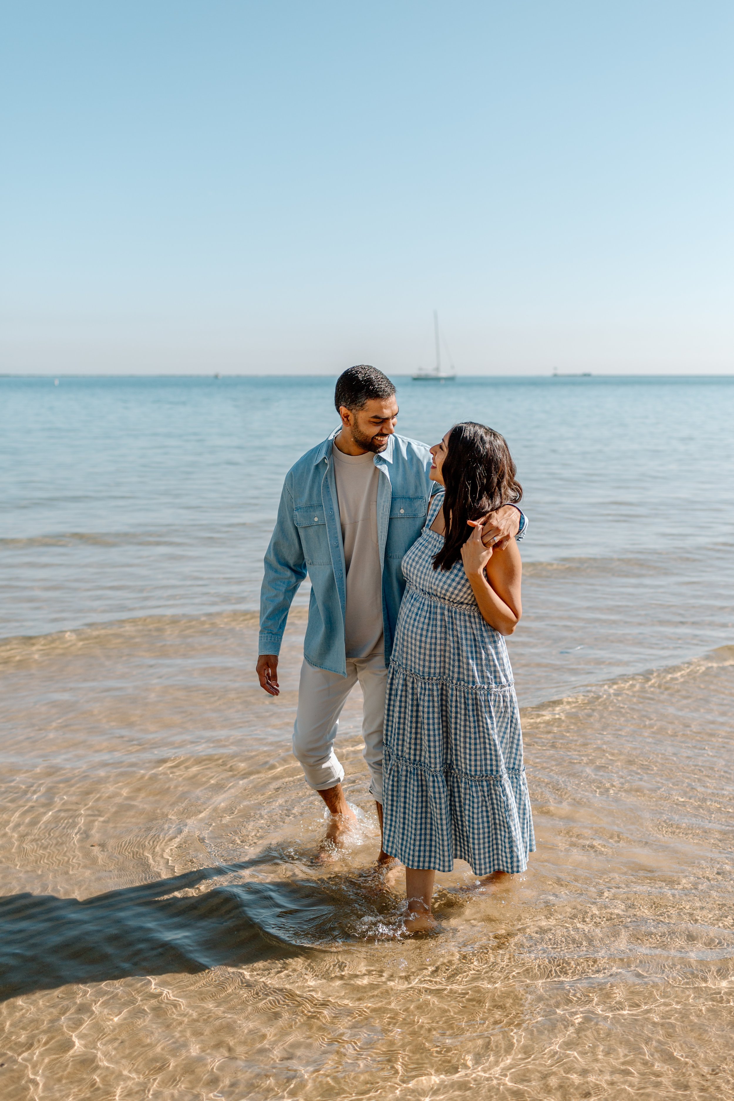  man and pregnant woman walk together on the beach of lake michigan 