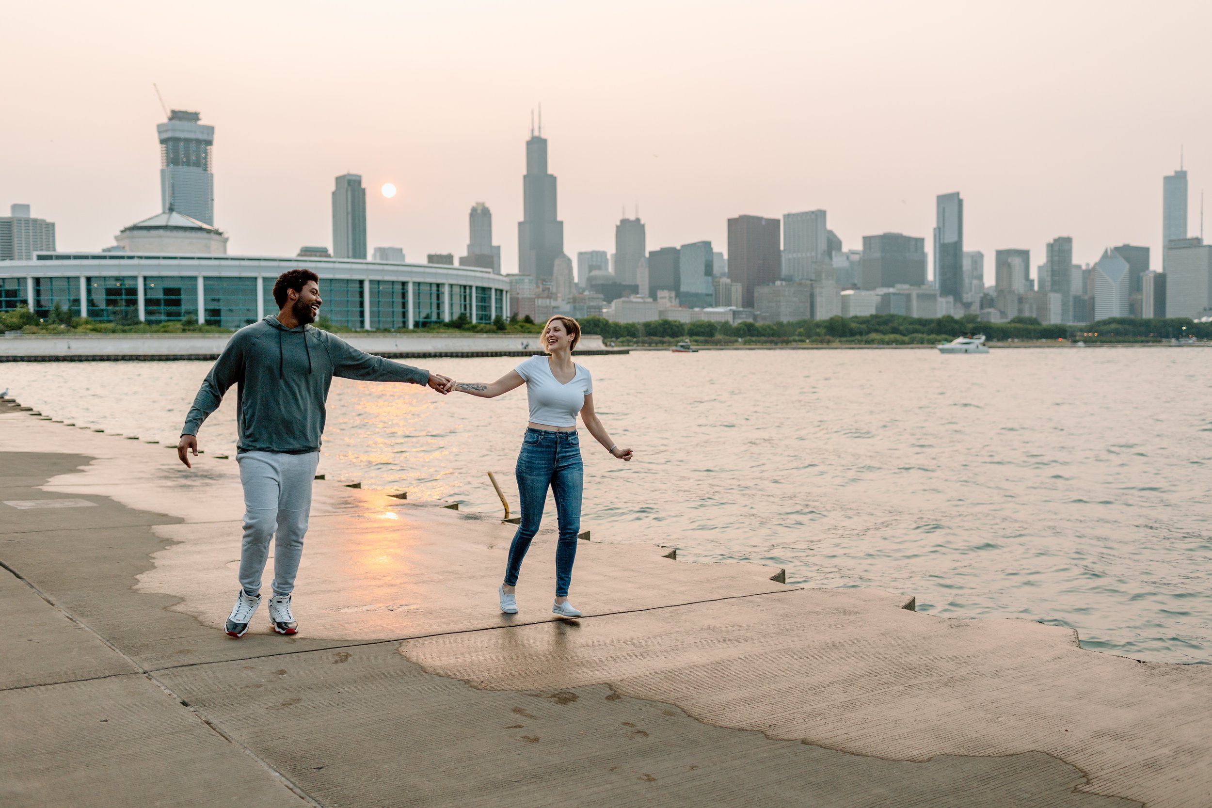  couple runs together and laughs in front of chicago skyline 