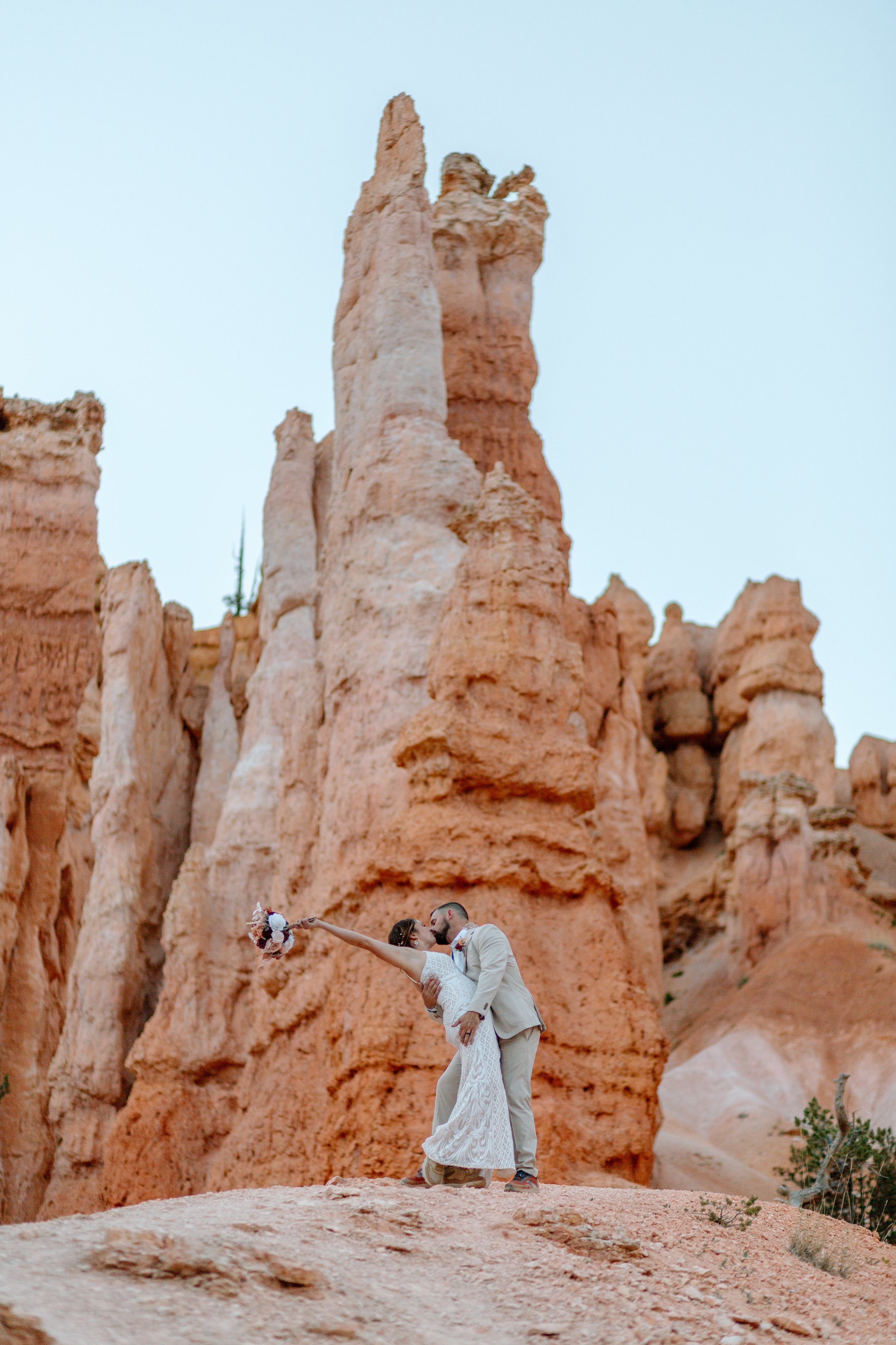  couple kiss and woman throws bouquet in the air during their bryce canyon elopement 