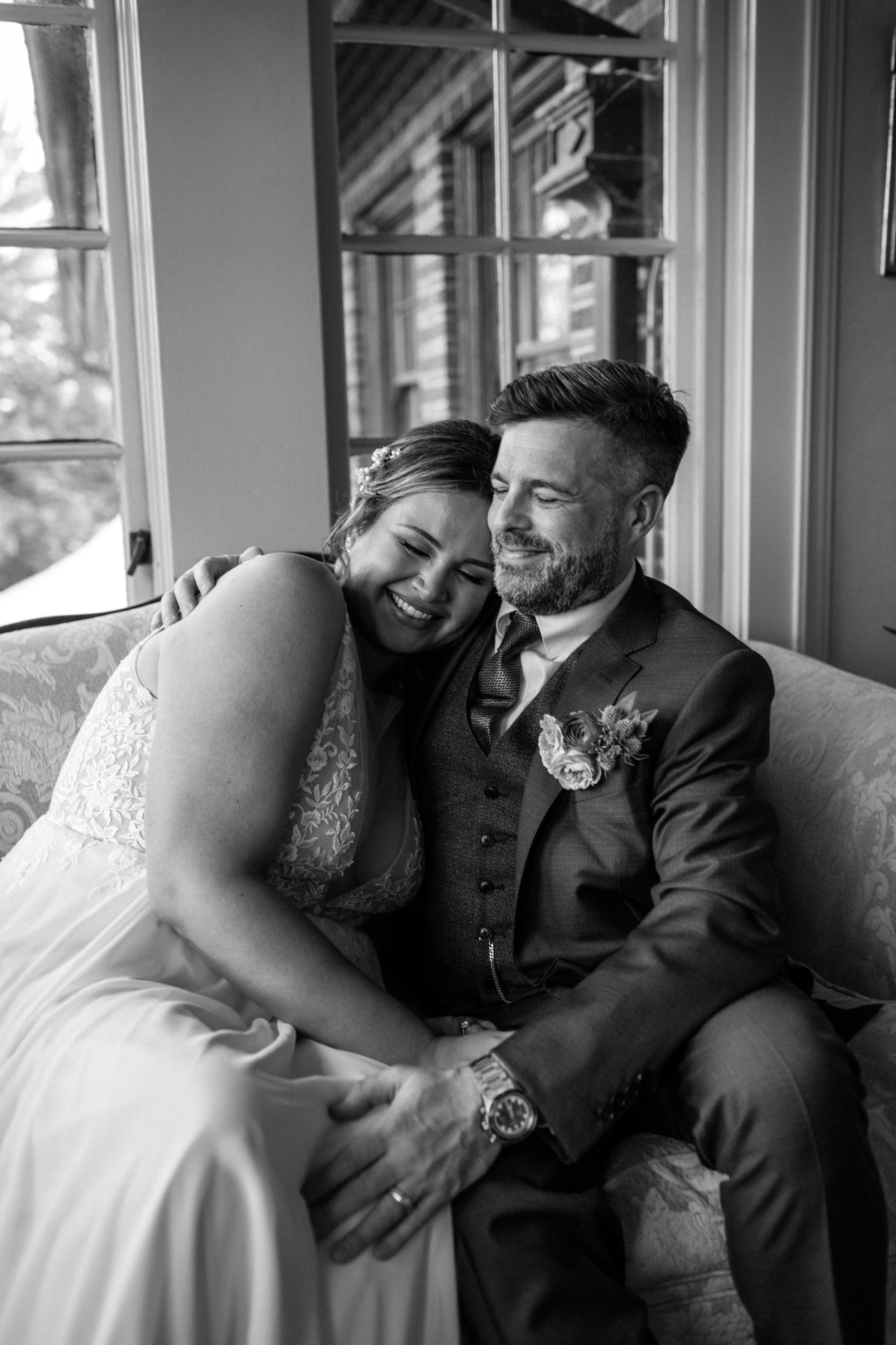  black and white photo of a wedding couple snuggling on a couch 