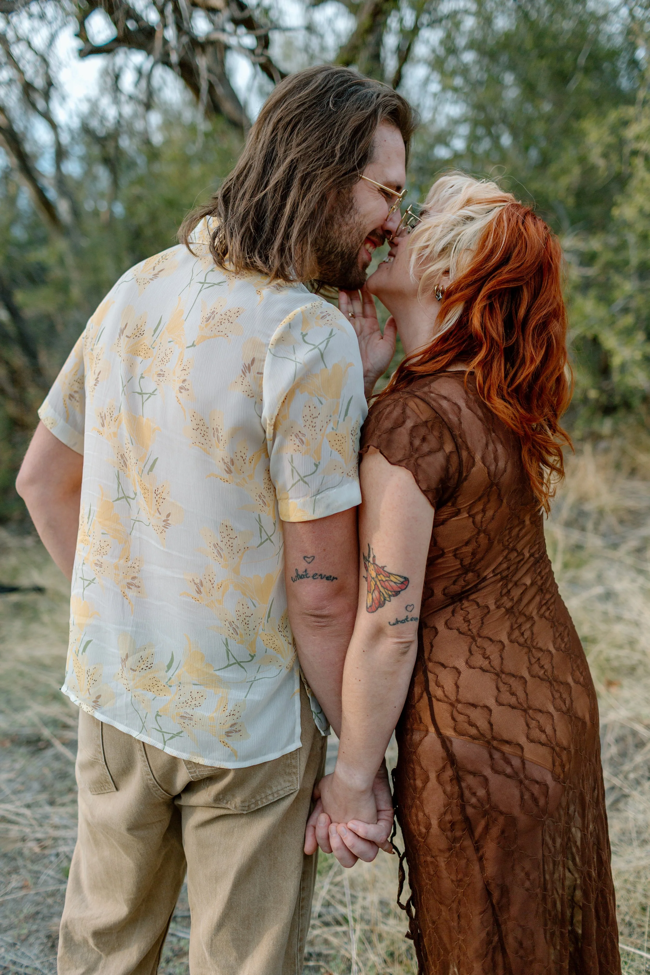  couple kisses while showing off matching tattoos by Tucson engagement photographer 