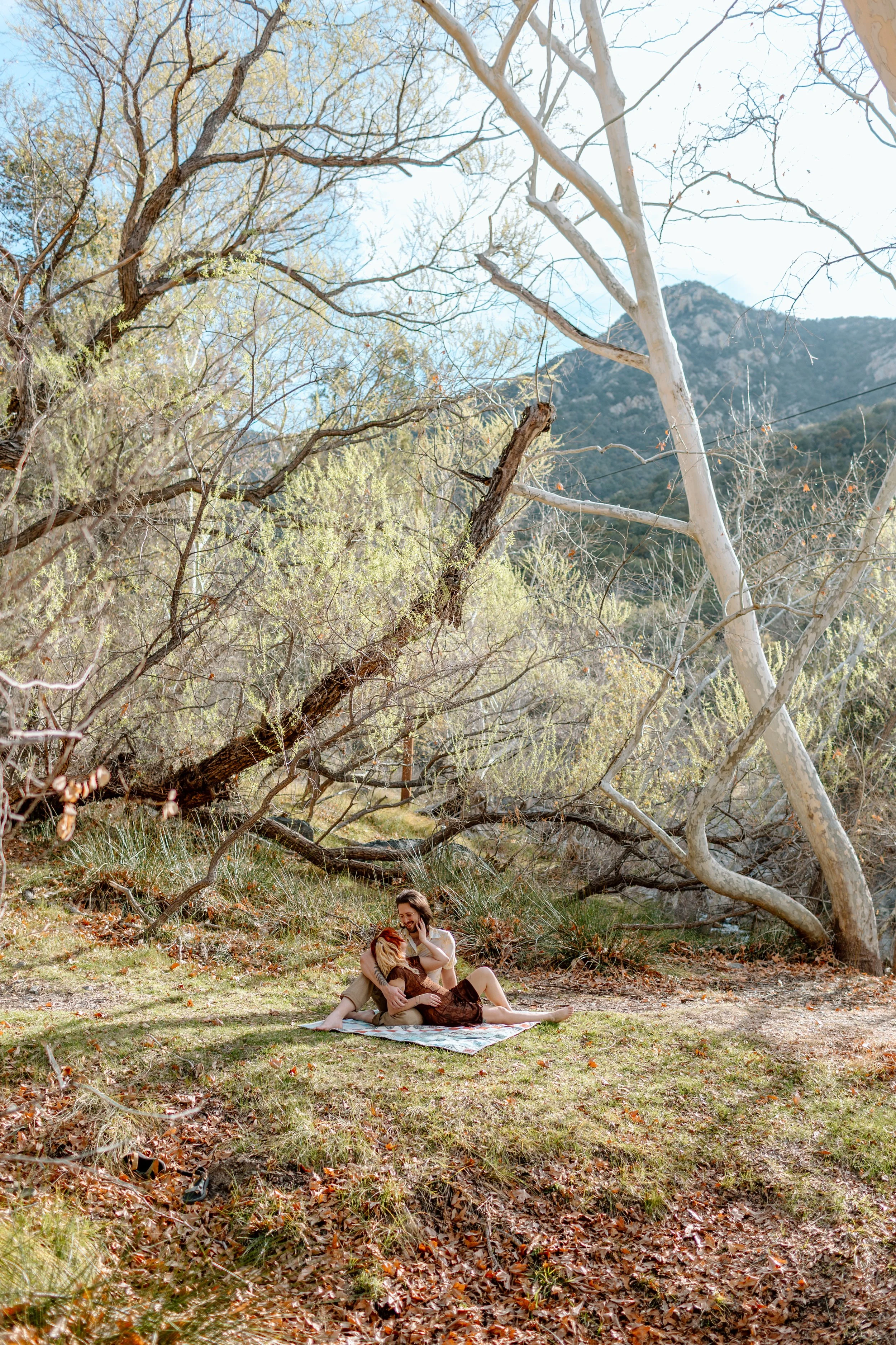 couple sit together on picnic blanket in the grass during Madera Canyon engagement session 