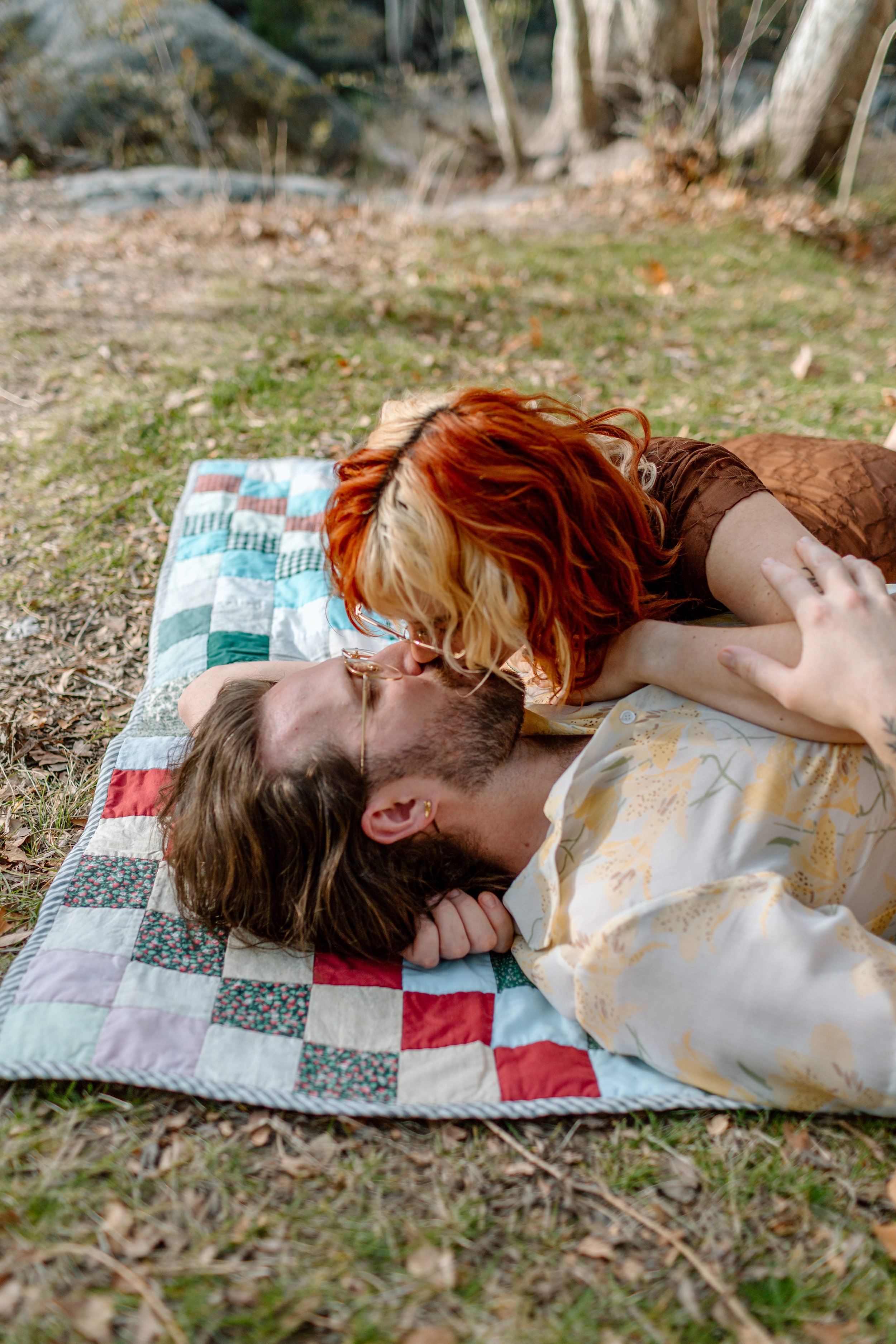  couple shares a kiss while lying on picnic blanket during Madera Canyon engagement session 