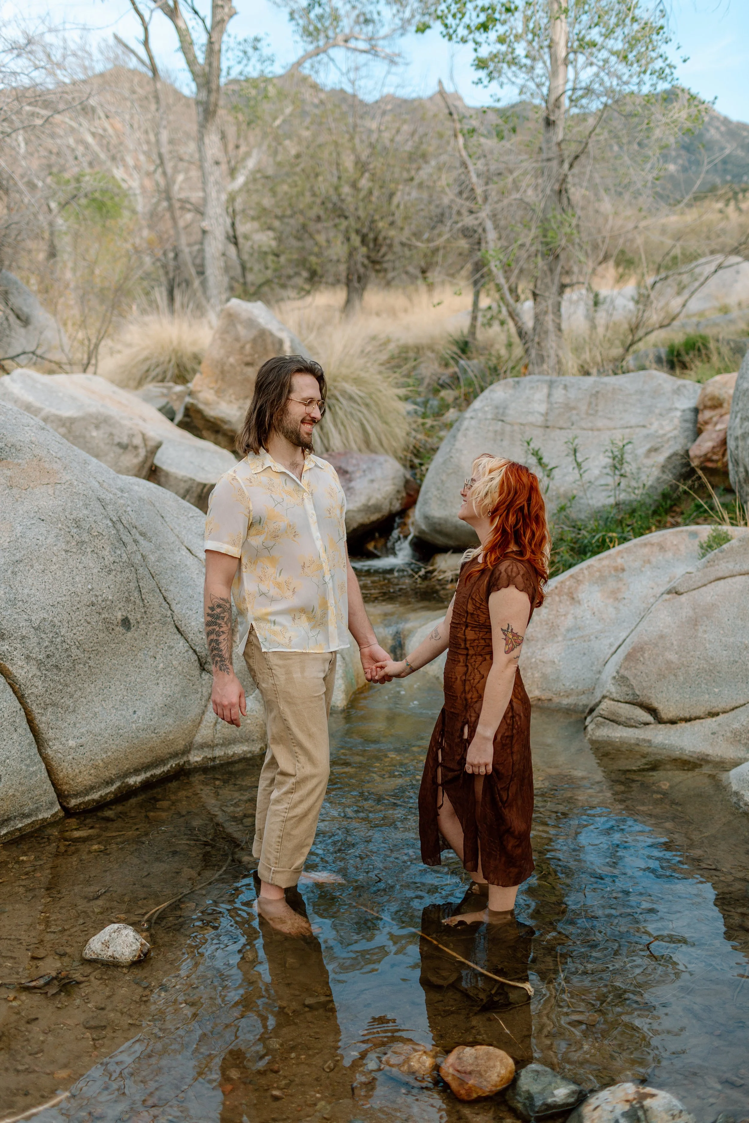  couple holds hands while standing in swimming hole at Madera Canyon 