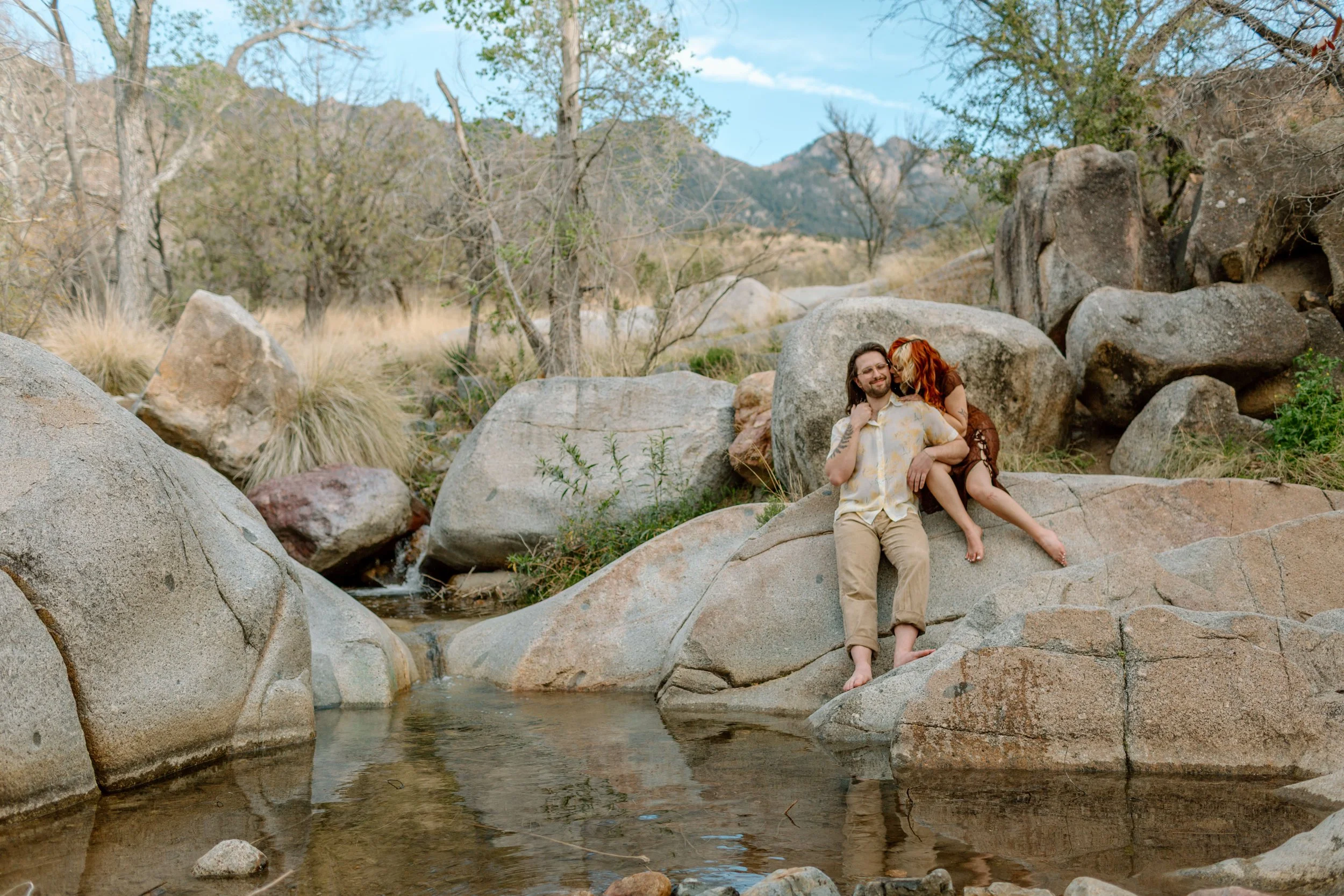 couple sits on a rock at a swimming hole for Tucson engagement session 