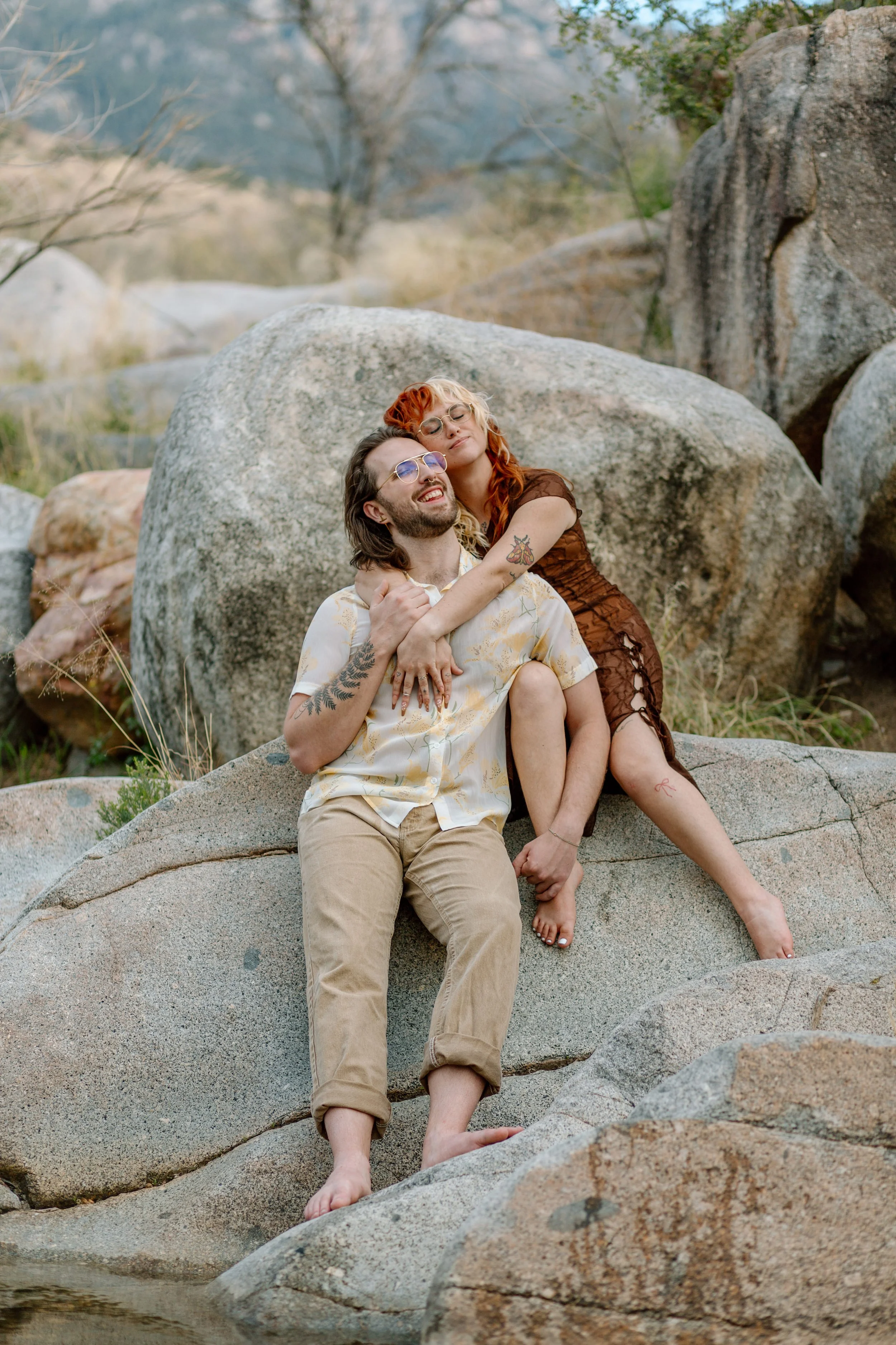  couple snuggles while sitting on a rock by Tucson engagement photographer 