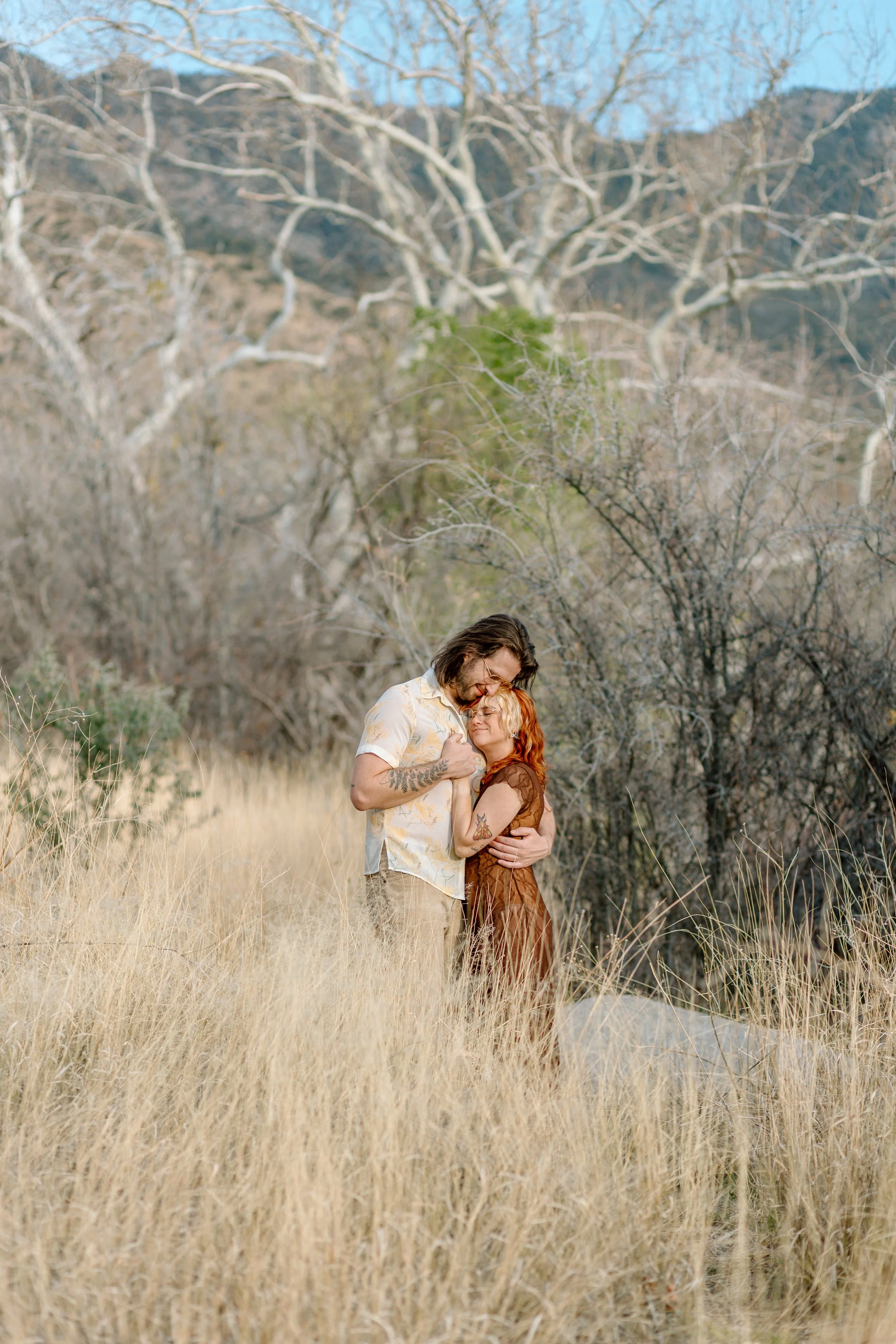  couple snuggles while standing in tall grass for Madera Canyon engagement session 