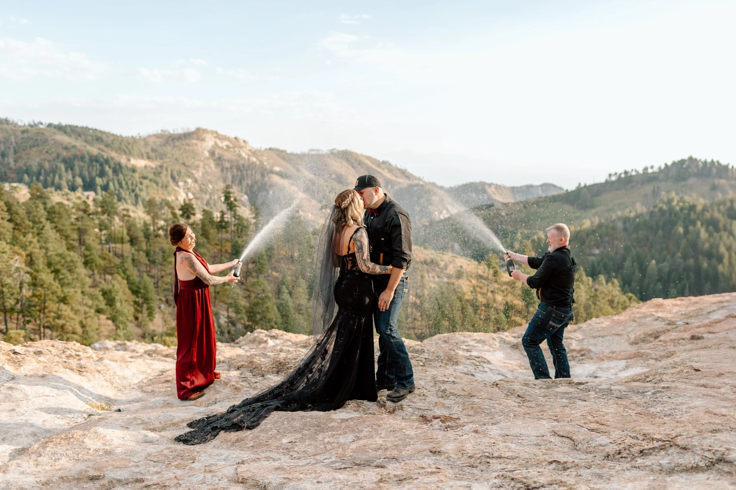 couple kisses during their tucson elopement while friends pop champagne behind them