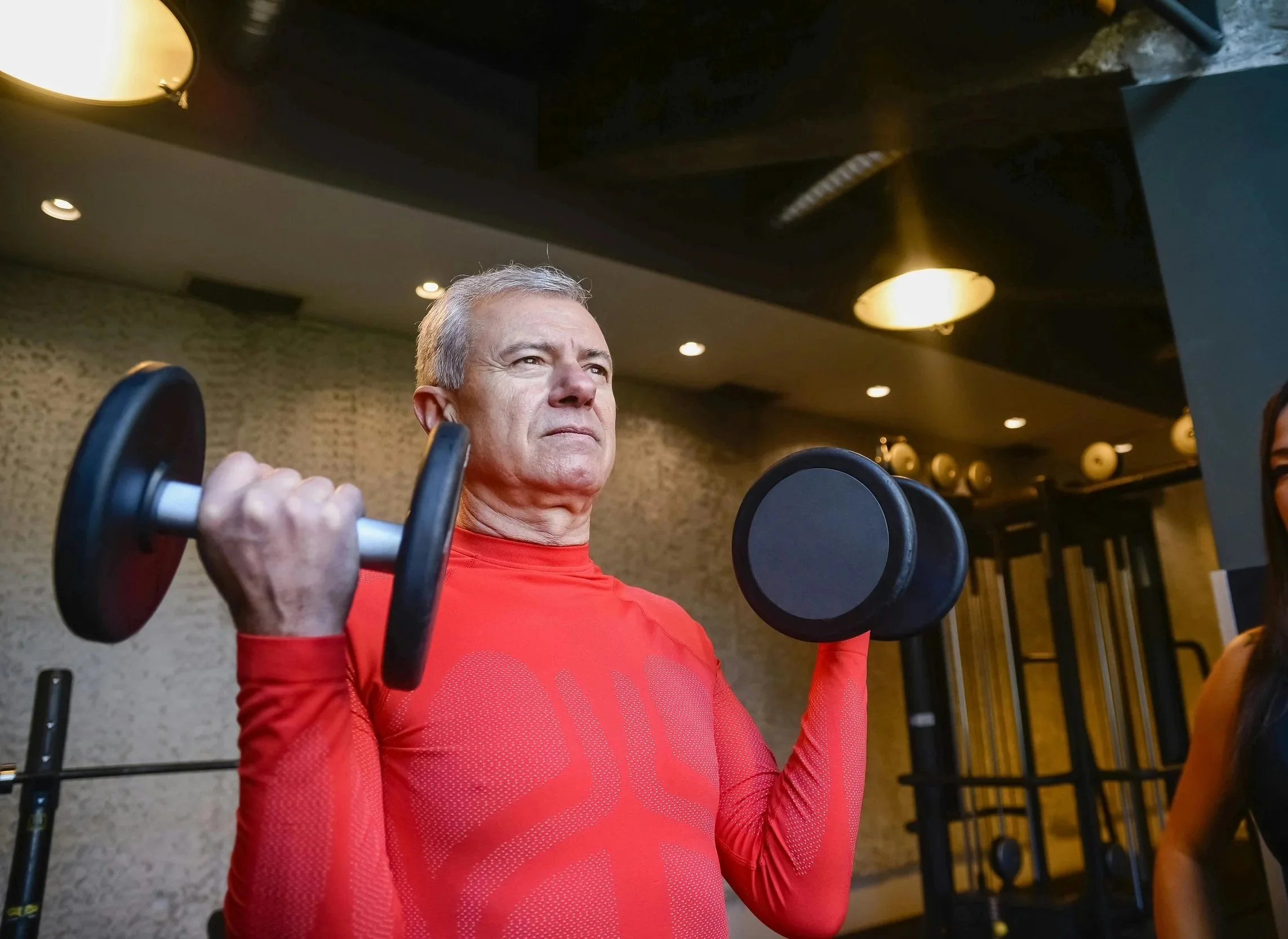Older man in his sixties performing a bicep curl during a strength training session