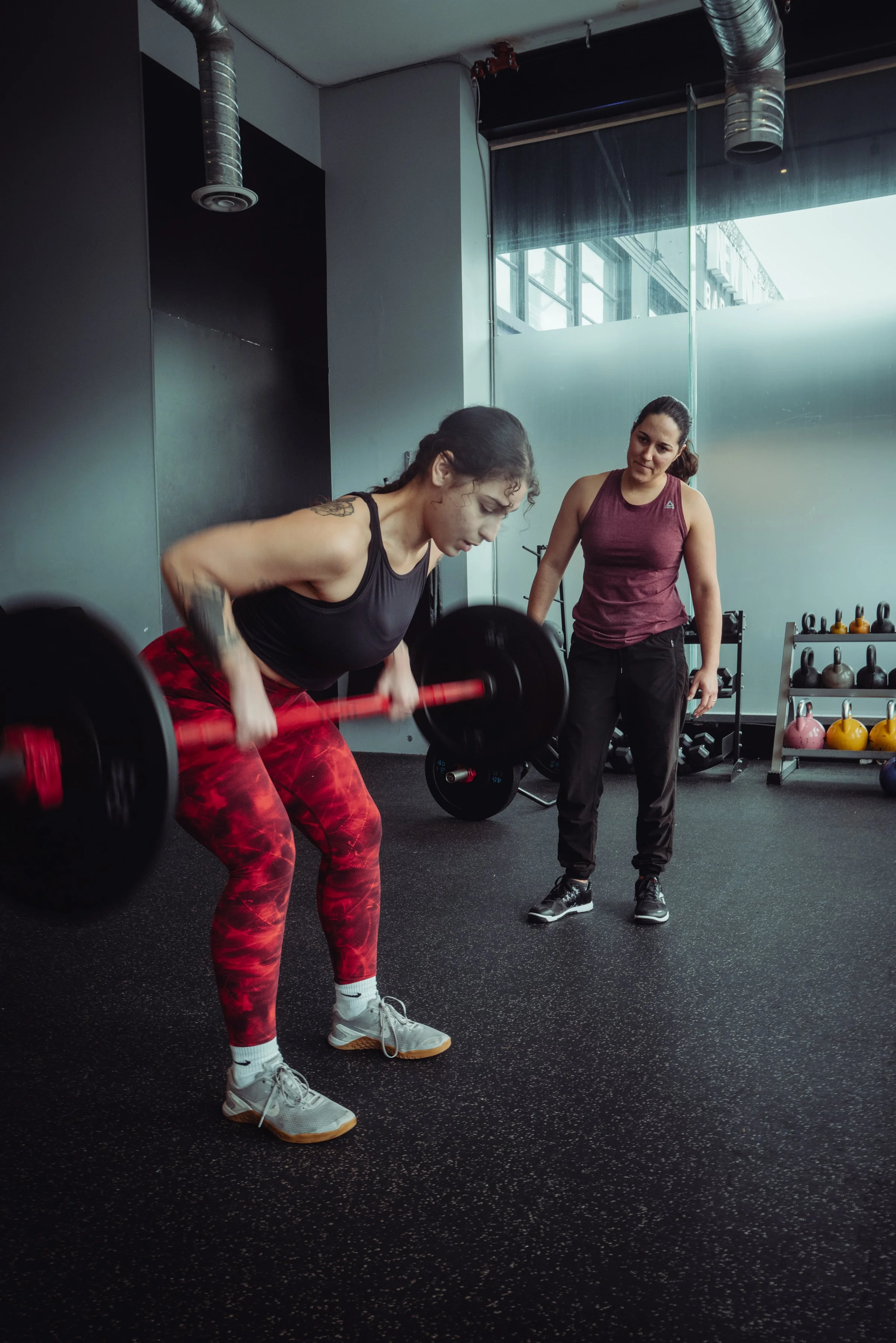 Strength coach supervising a client's barbell row technique during 1-on-1 training at Avos Strength in Vancouver