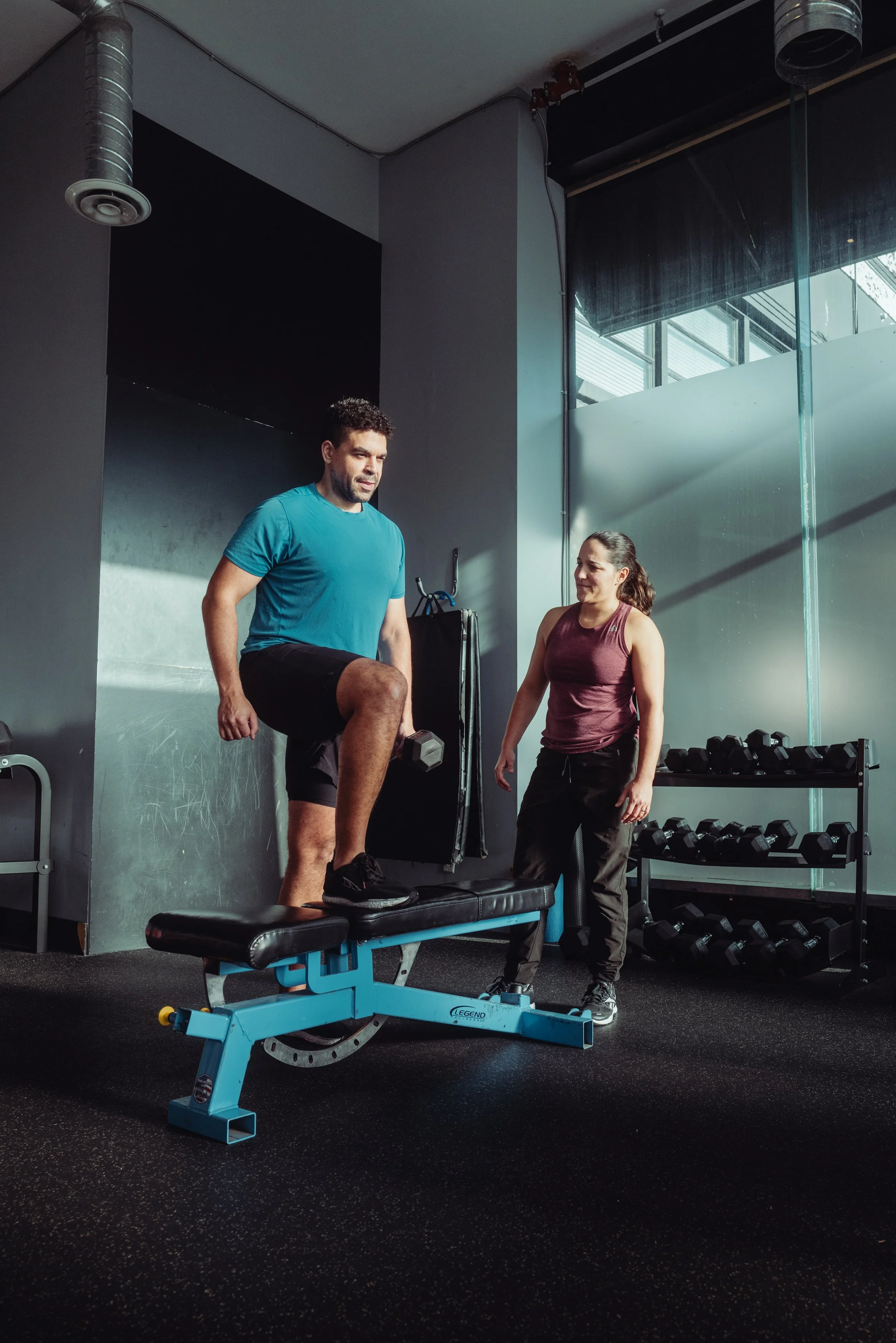 Personal training coach guiding a client through a weighted step-up during 1-on-1 training in Vancouver