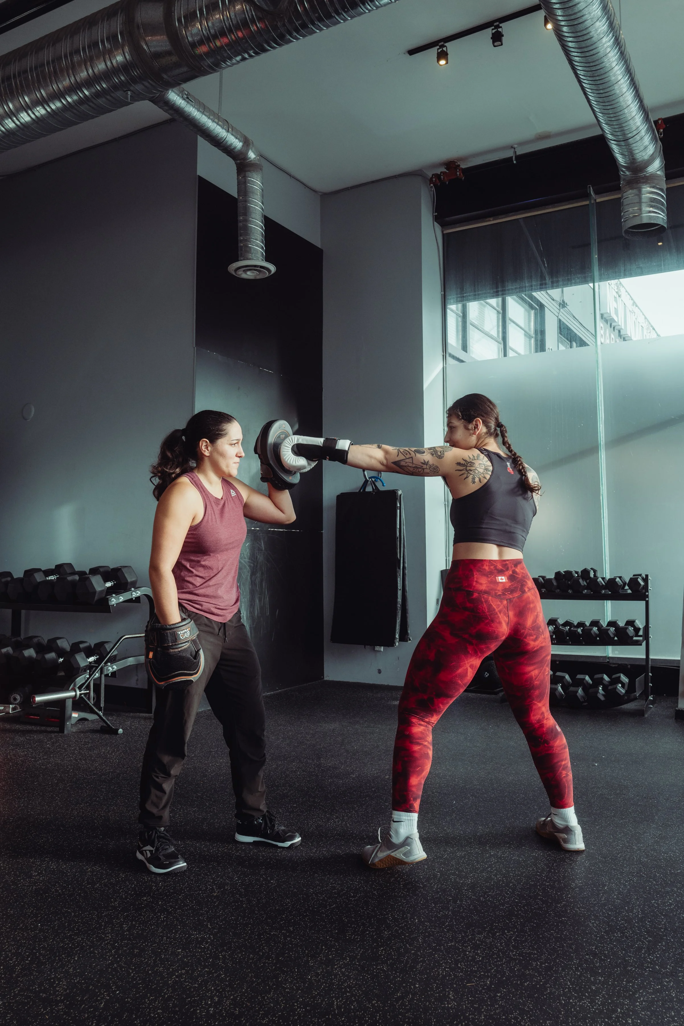 Boxing coach holding pads for a client practicing a jab during boxing training in Vancouver