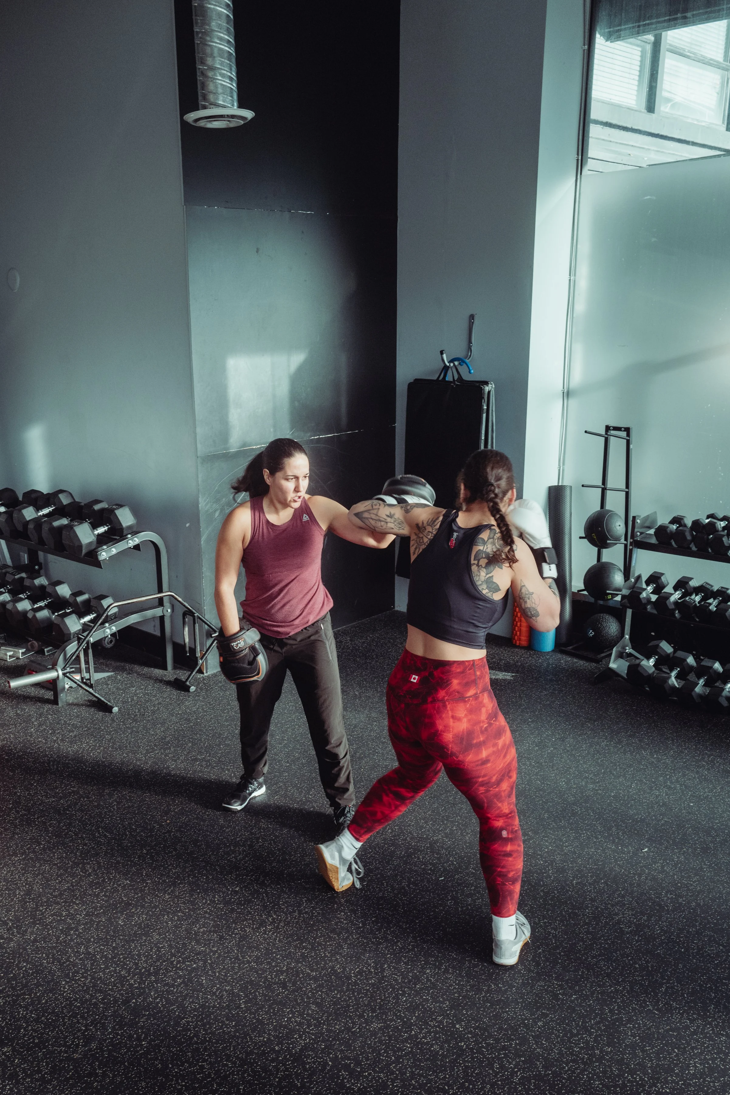 Client throwing a hook on focus mitts with a boxing coach in Vancouver