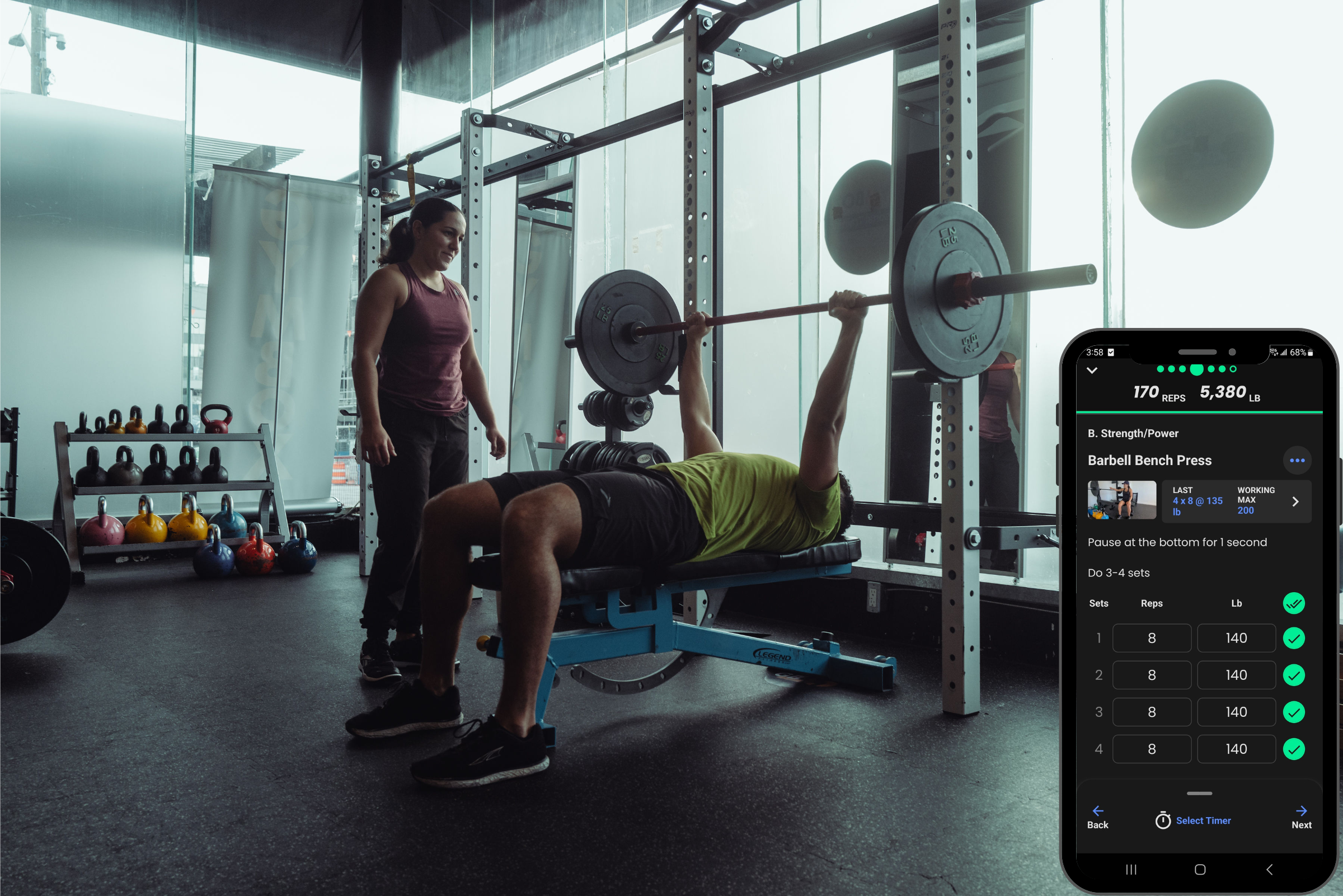 Coach spotting a bench press with the TrainHeroic app tracking sets for hybrid training in Vancouver