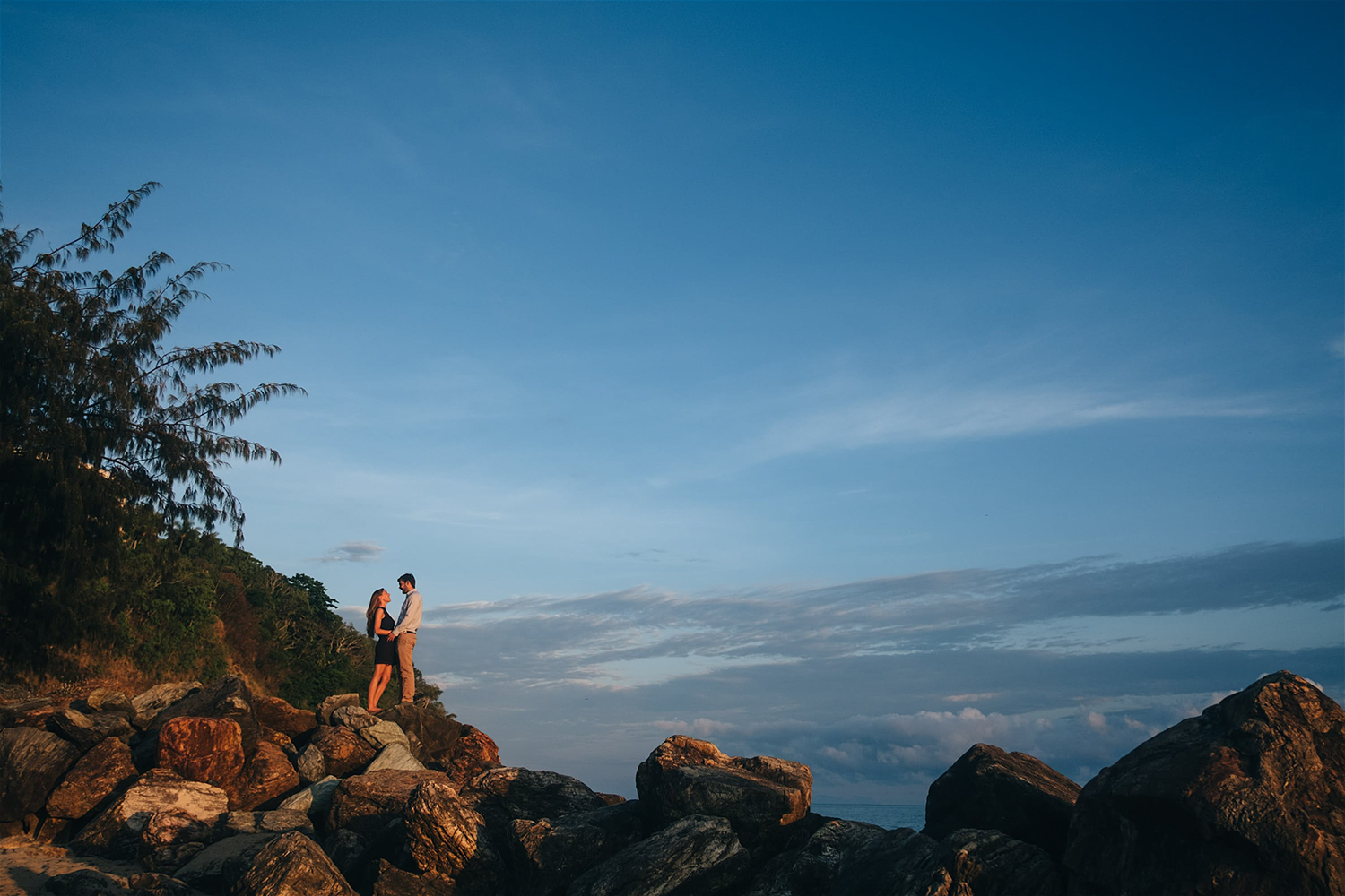 couple-standing-on-big-rocks-by-beach.jpg