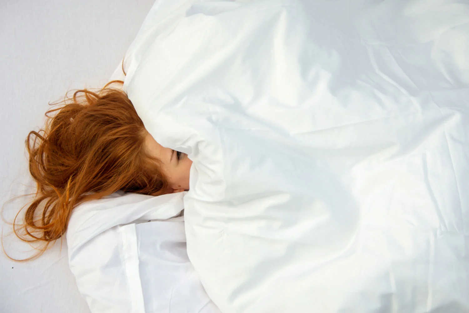 Рыжая лежит на кровати. Женщина с рыжими волосами. Рыжая девушка в белой рубашке. На мятых простынях рыжая девушка. Рыжая девушка в постели.