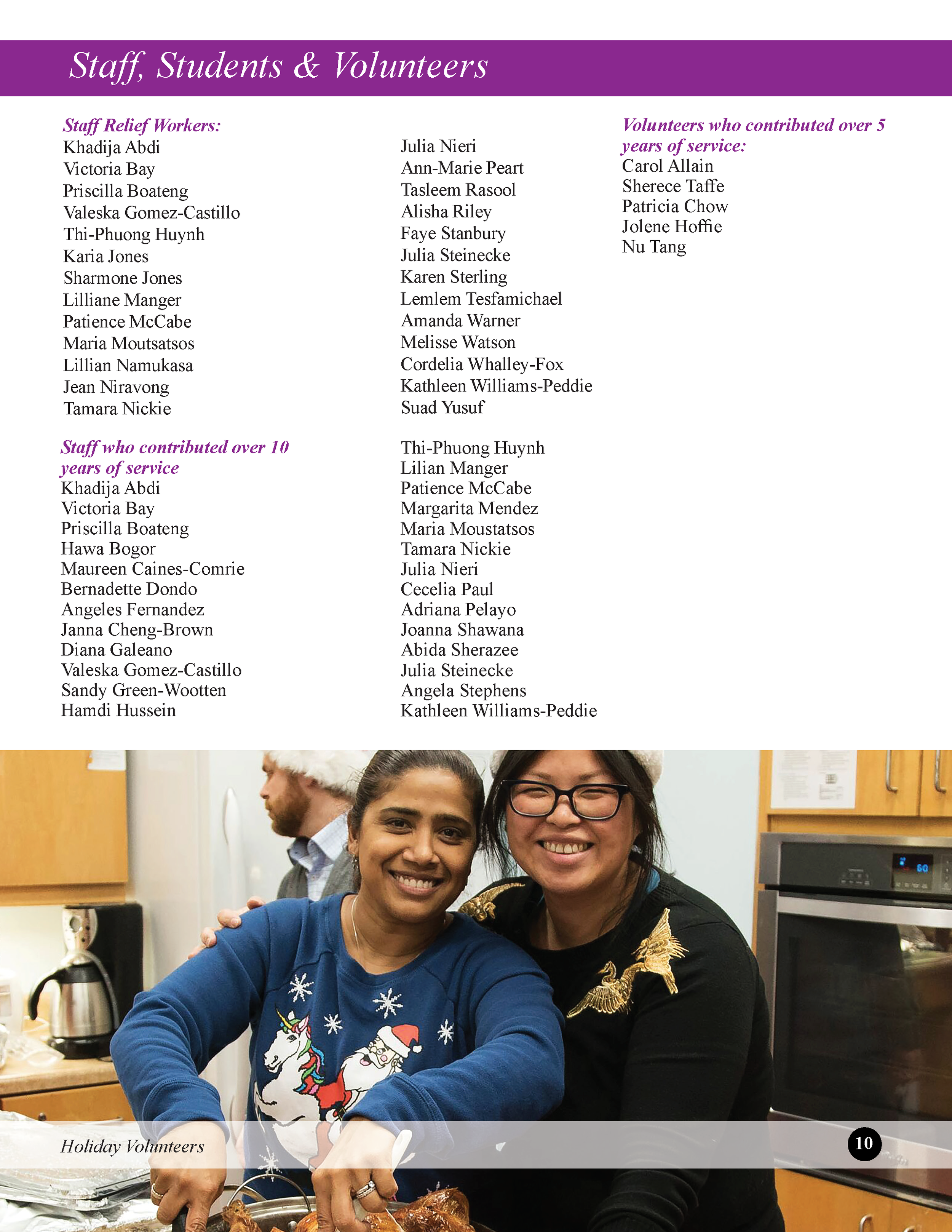 Two women smiling and posing for a photo in a kitchen during a holiday volunteer event, with a woman wearing a sweater decorated with a festive unicorn and Santa Claus in the foreground.