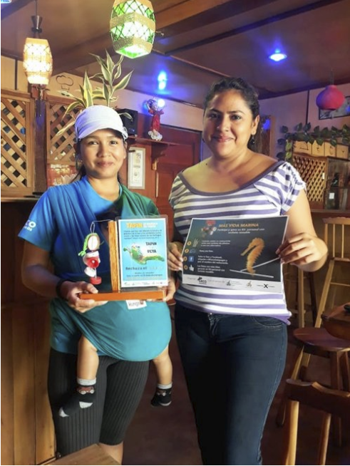 Figure 6. Daniela Chalén with her son and one of San Cristobal’s leaders in the plastic reduction campaign, in her place of business. Photo: Ashleigh Klingman