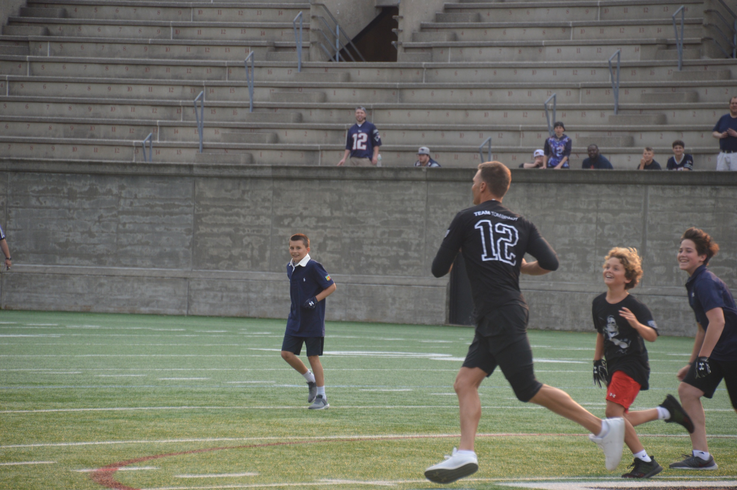 Two athletes rush Tom Brady as his son, Benjamin looks on.