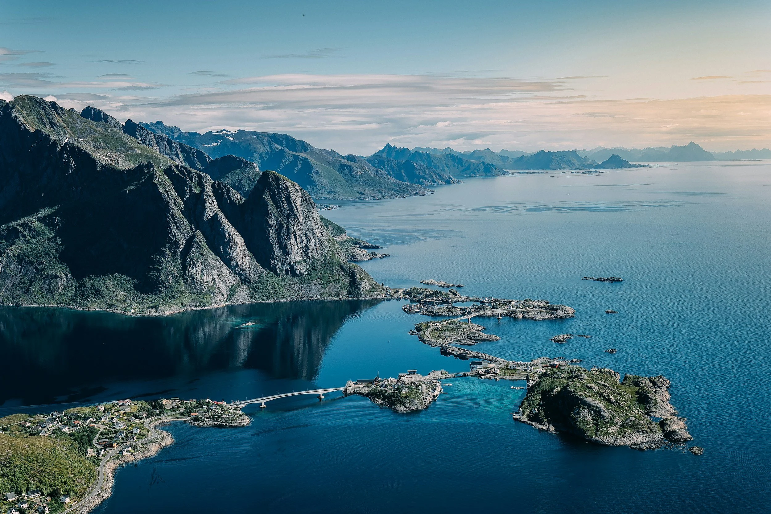An aerial view of the Norwegian Fjords with cliffs rising and reflecting in the clear turquoise water