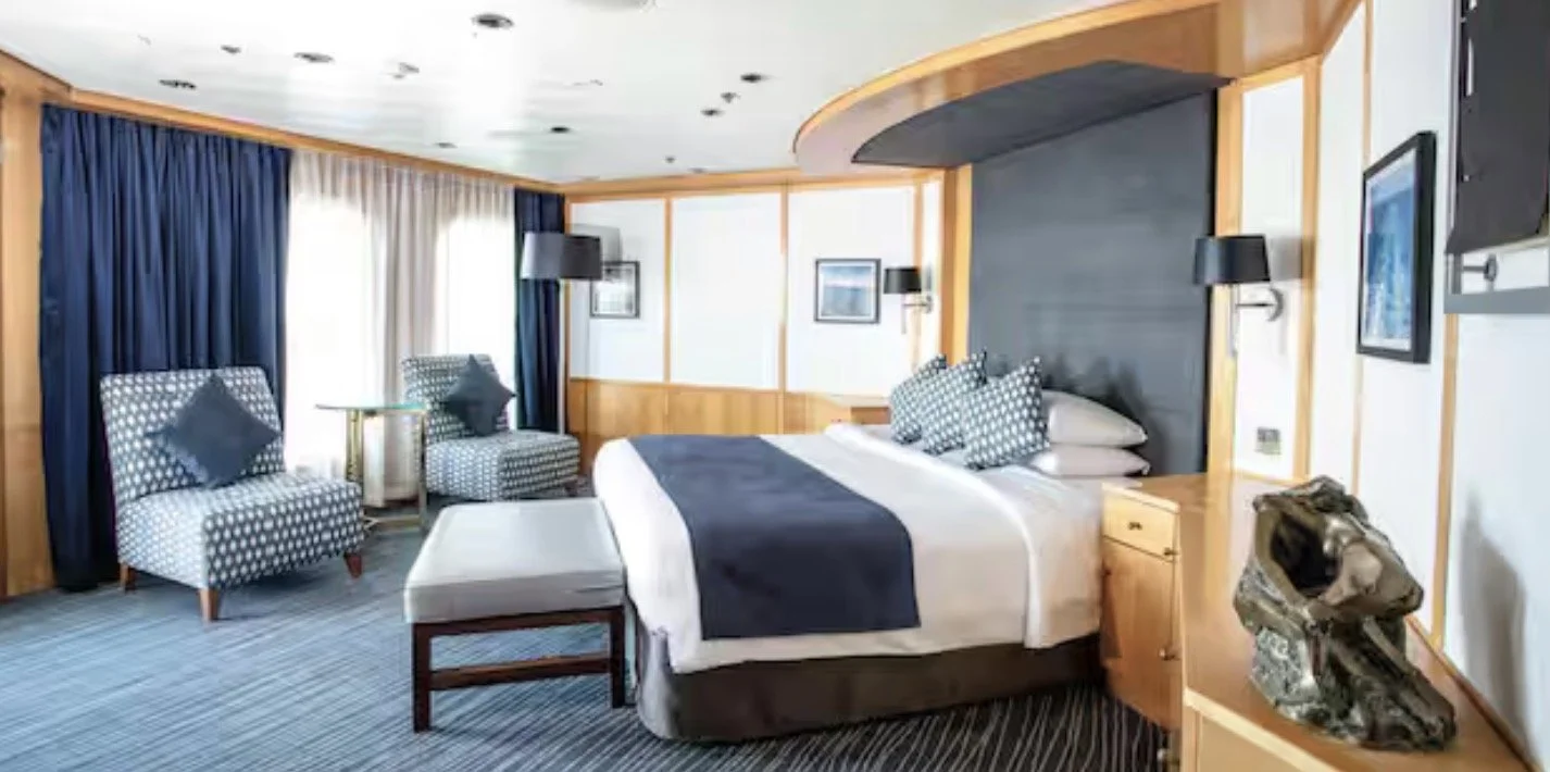 Marella Cruises Royal Suite Budroom with blue upholstery and light wood accents.
