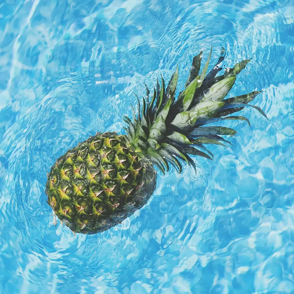 Pineapple floating in blue water