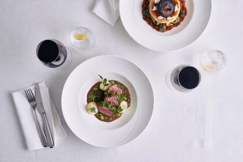 Flat lay of a lamb dish on white crockery and white linen on P&O Cruises Celebration Night at The Chef’s Table