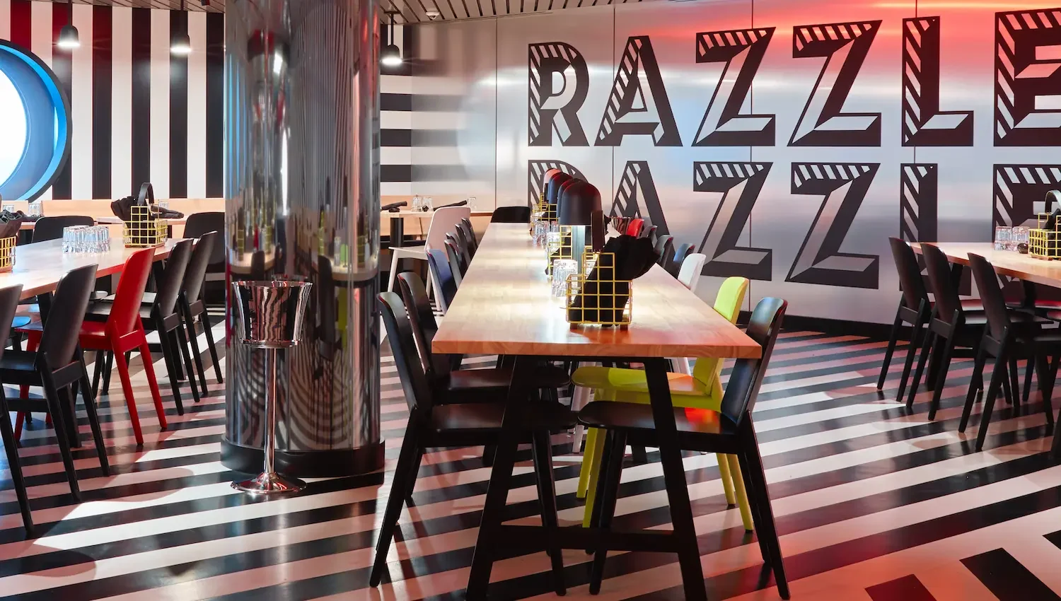 Virgin Voyages Razz.e Dazzle Restaurant with iconic black and white striped camouflage decor with red accents.