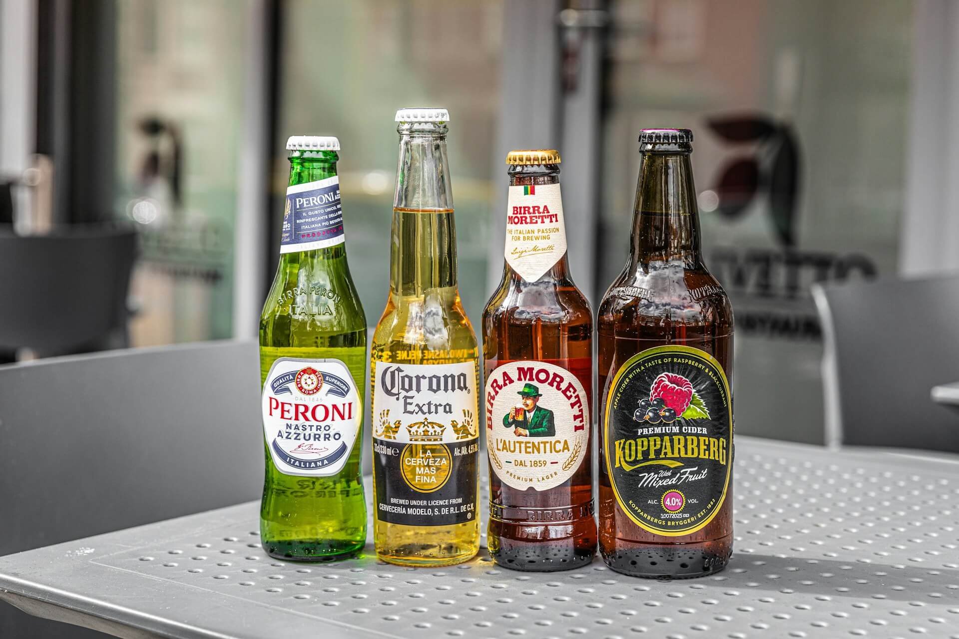 Four assorted bottled beers standing on a metal table
