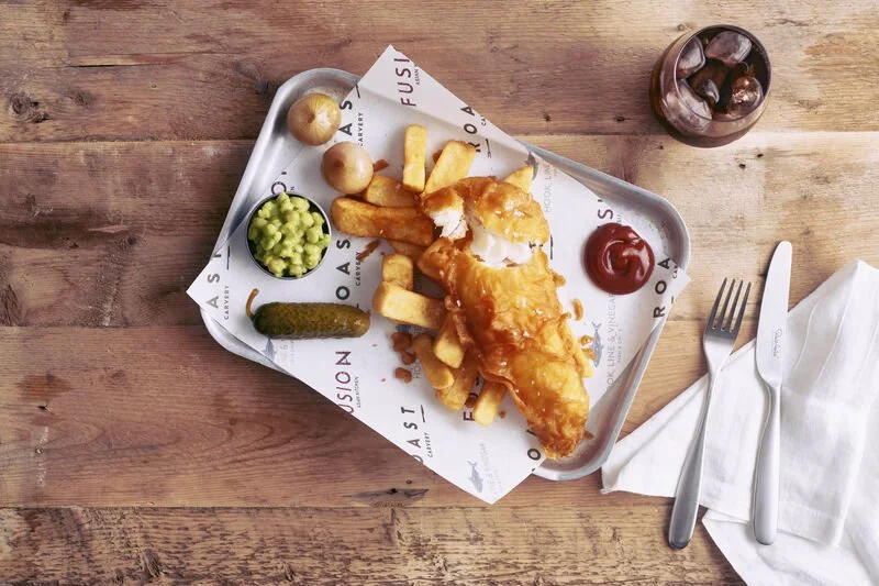 Flat lay of Battered Fish and chips with pickles and mushy peas on a printed paper cover on a metal tray - Hook, Line & Vinegar,The Quays on P&O Cruises Arvia and Iona cruise ships