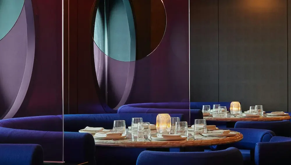 A window table set for dinner in Virgin Voyages Pink Agave restaurant.