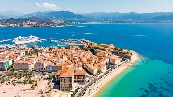 Mediterranean terracotta roofed buildings in foreground with cruise ship on blue sea and islands in background