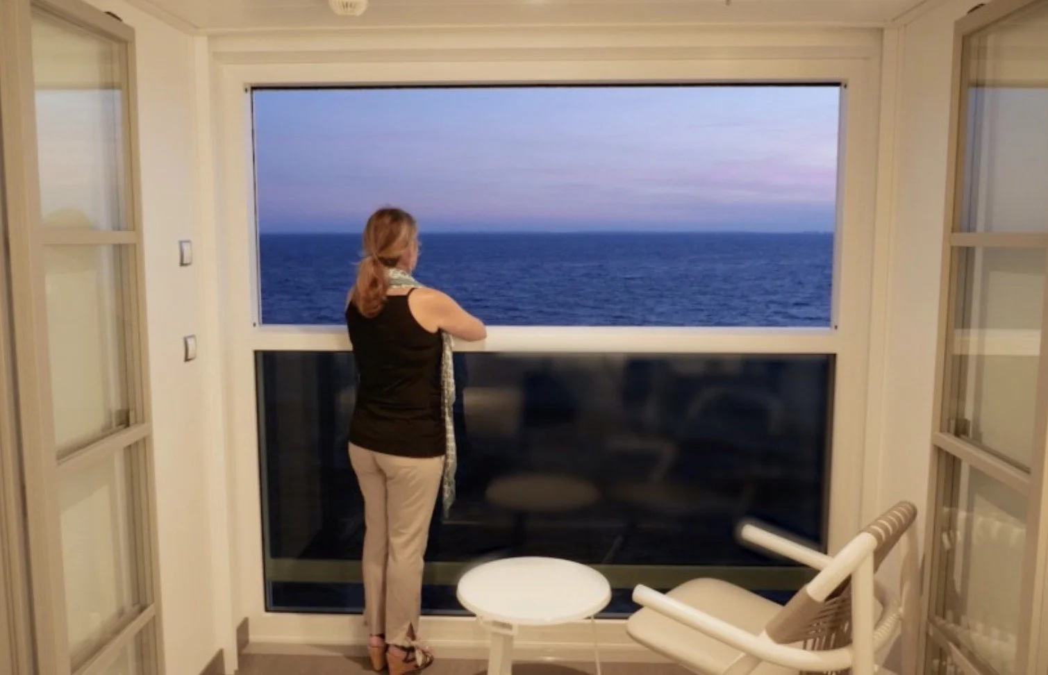 Woman standing at Infinite Veranda on Celebrity Cruise overlooking the ocean.