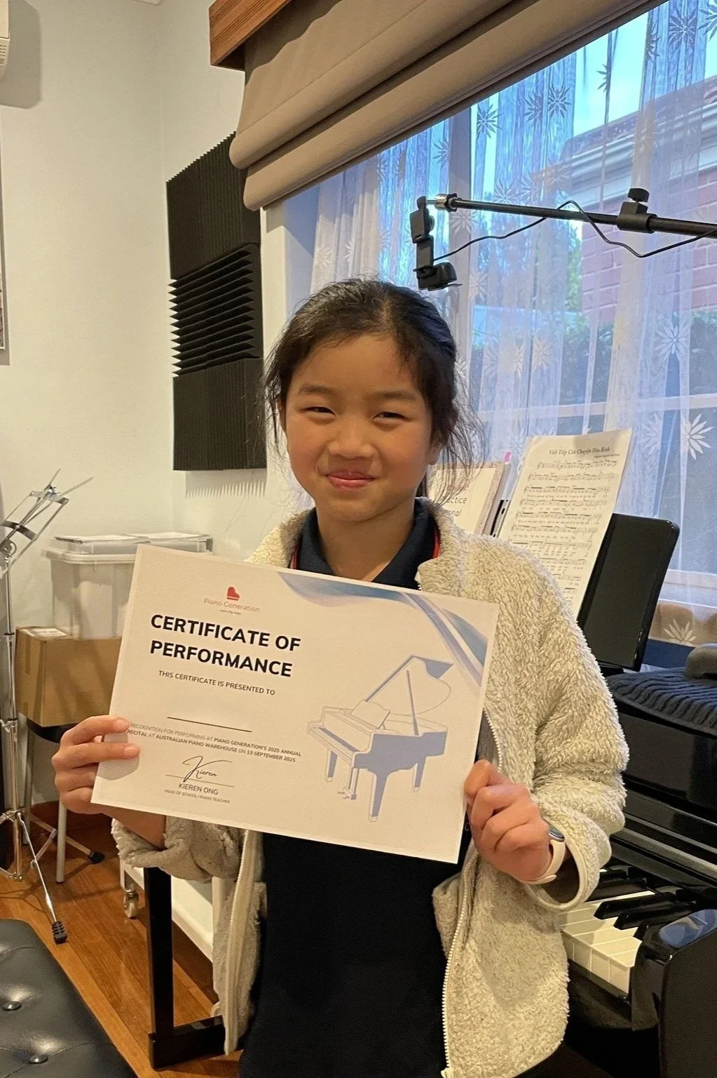 Young Piano Generation student holding her Certificate of Performance in a piano studio.