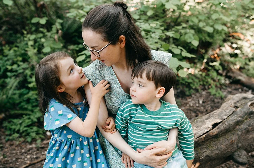 a mother sits on a log at a park in seattle family photosession