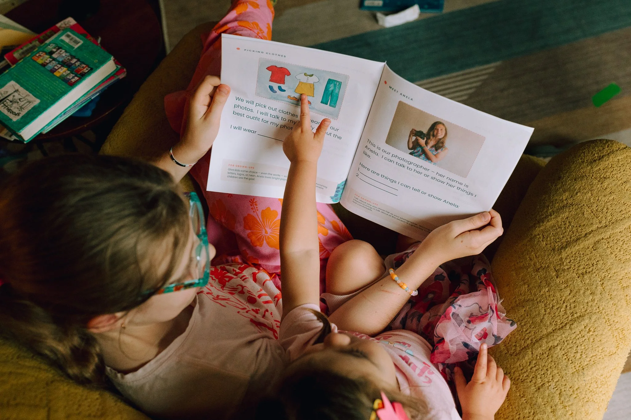 Two children reading My Family Photo Day together, looking at the pages that show them what to expect at their photo session.
