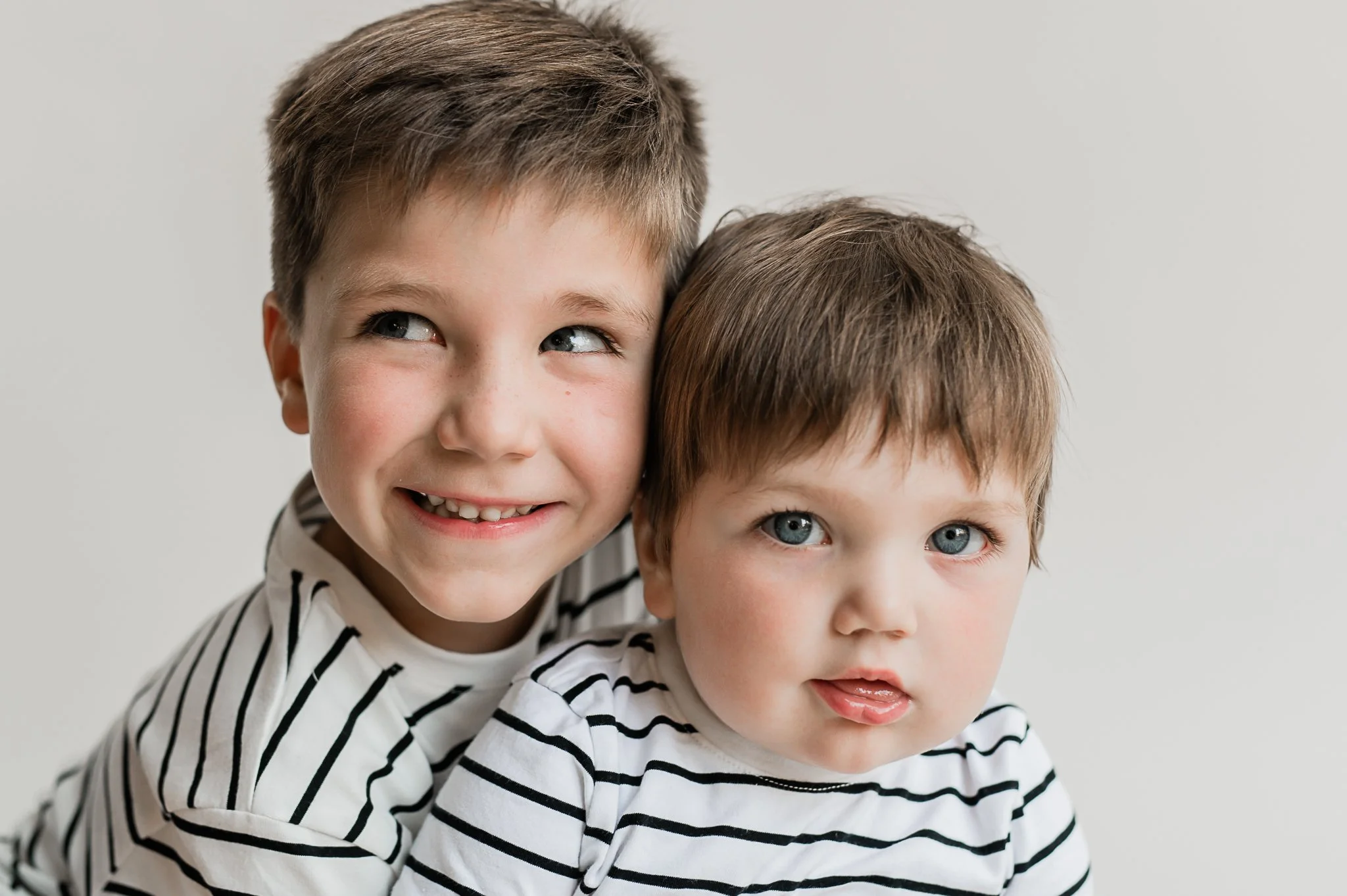 two brothers hug at a studio with a white backdrop