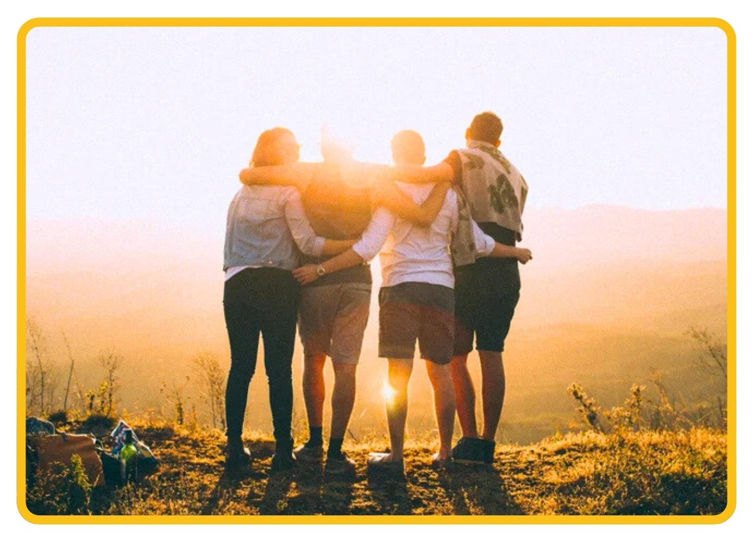 Four adults hugging in a sunny hilltop