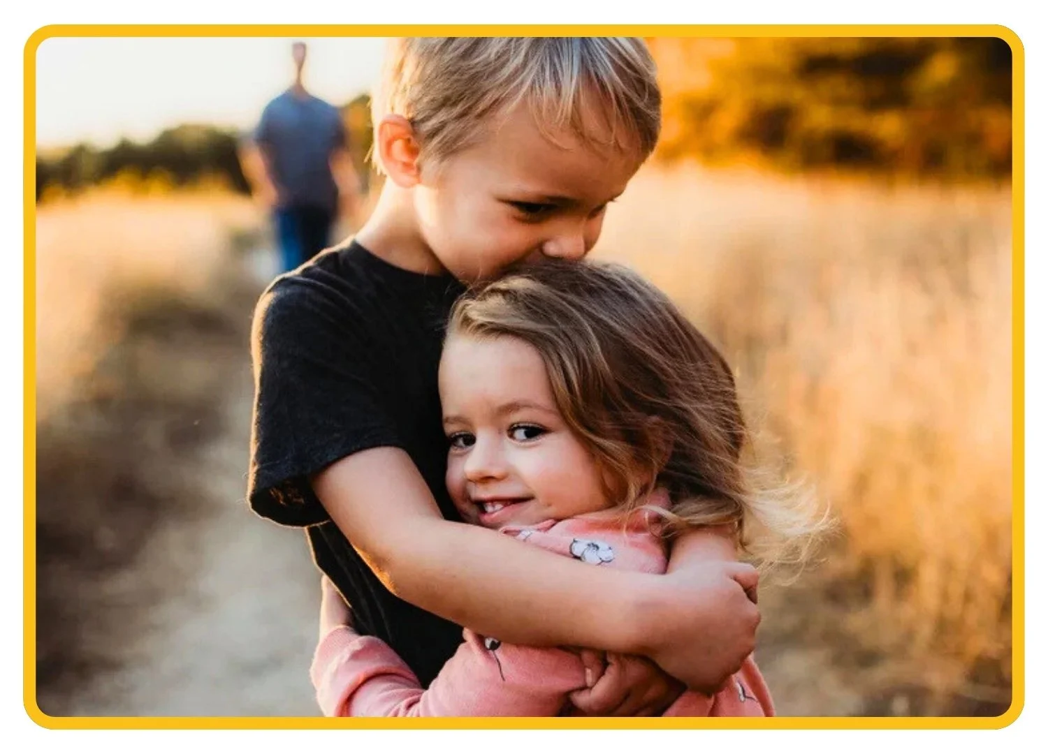 Two young children hugging in a sunny field