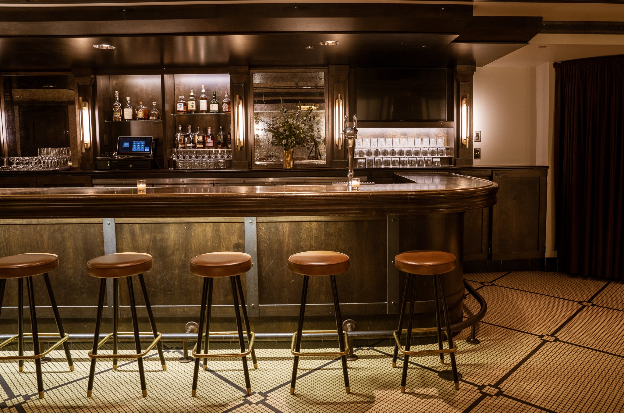 Close-up shot capturing the bar's corner, featuring brass lighting fixtures illuminating the area behind the bar counter.